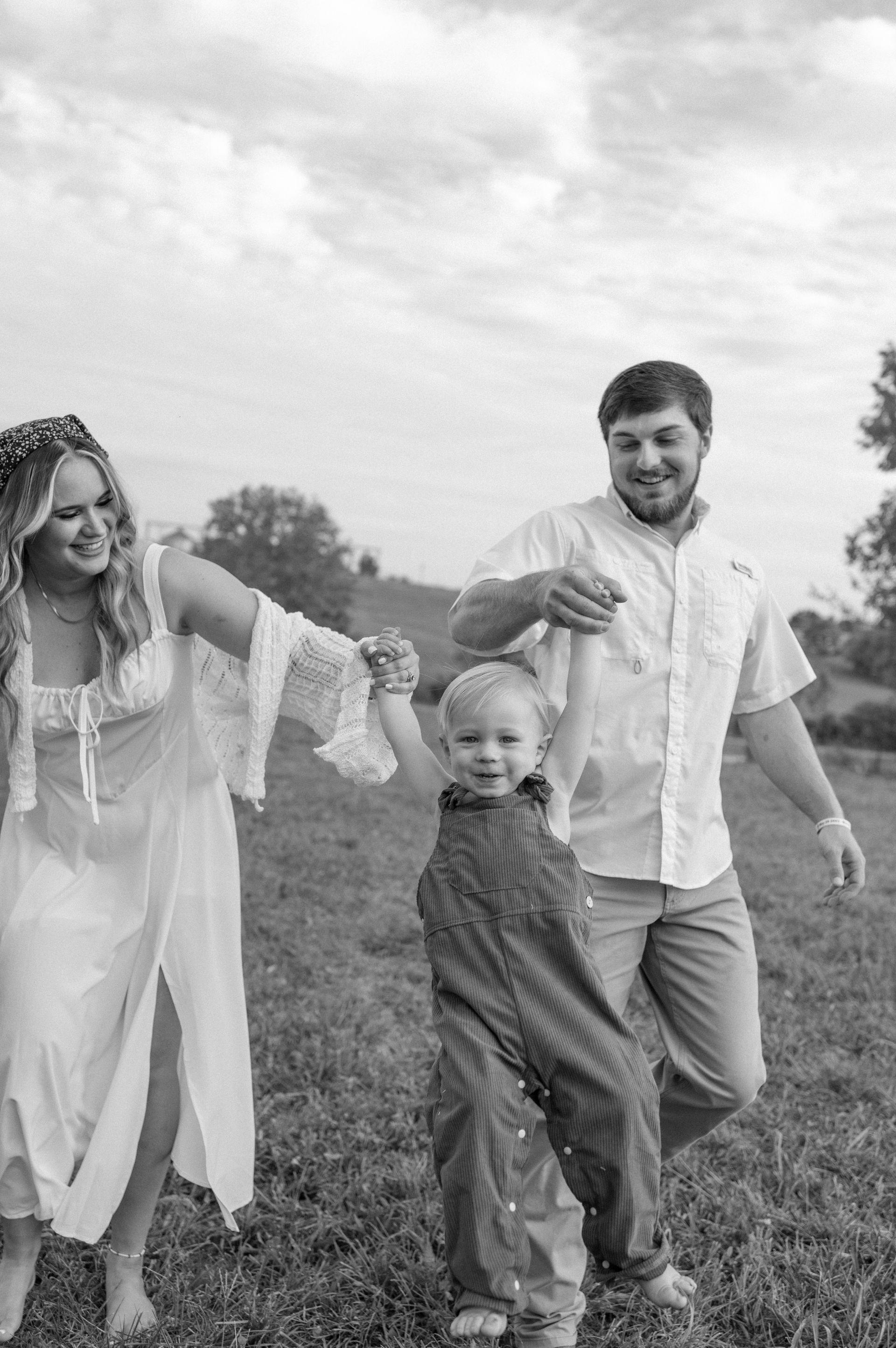 A black and white photo of a family holding hands in a field.