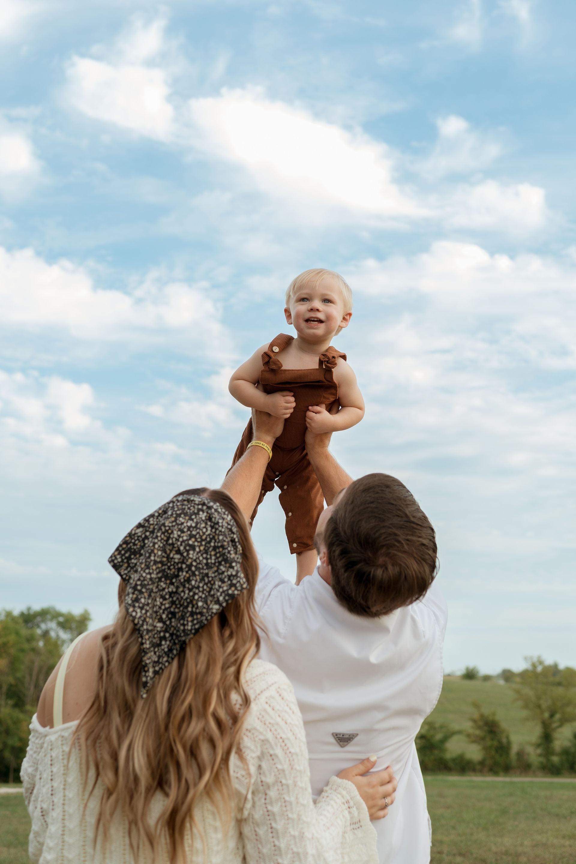 A man and a woman are holding a baby in the air.