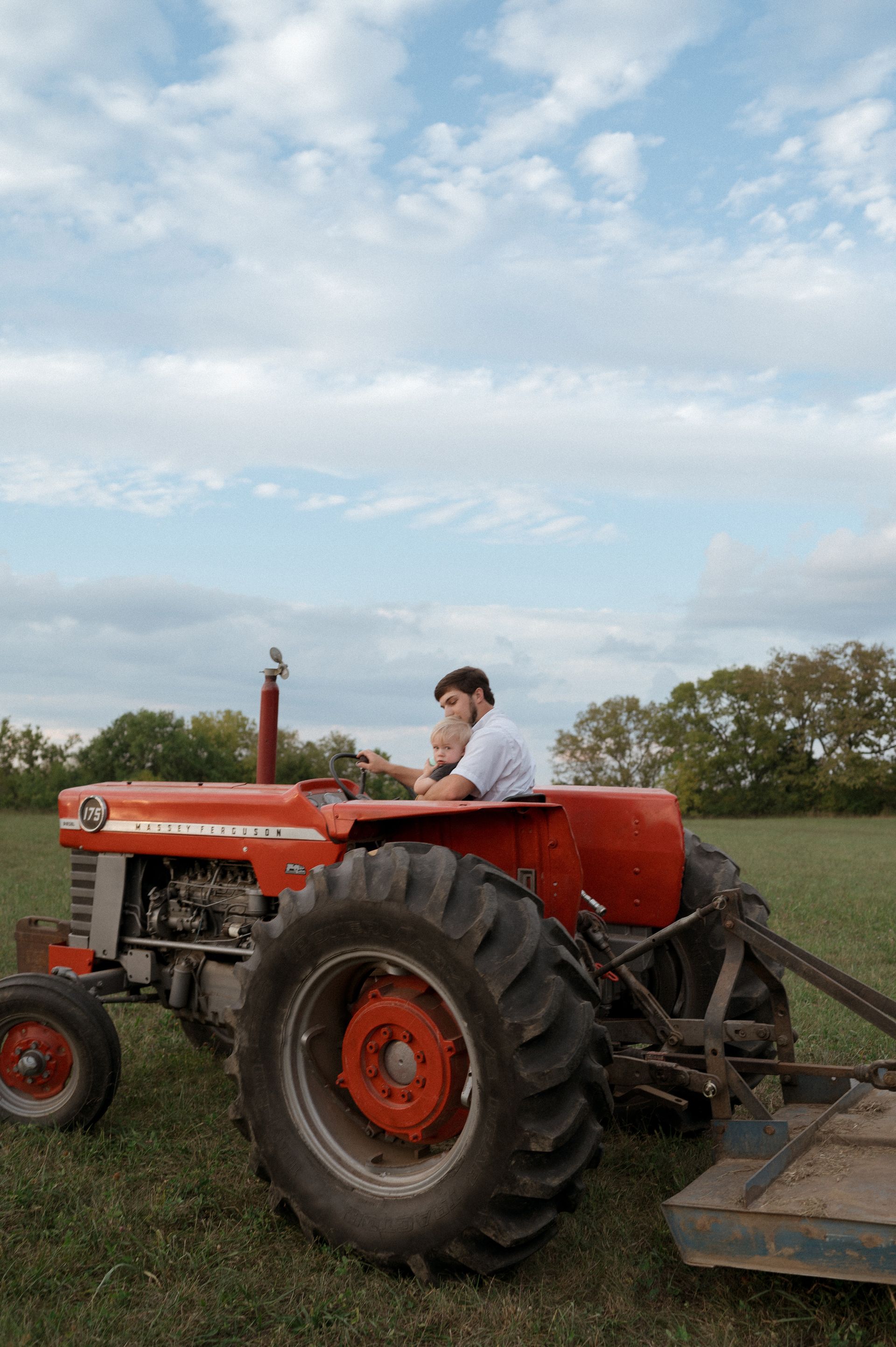 A man is driving a red massey ferguson tractor