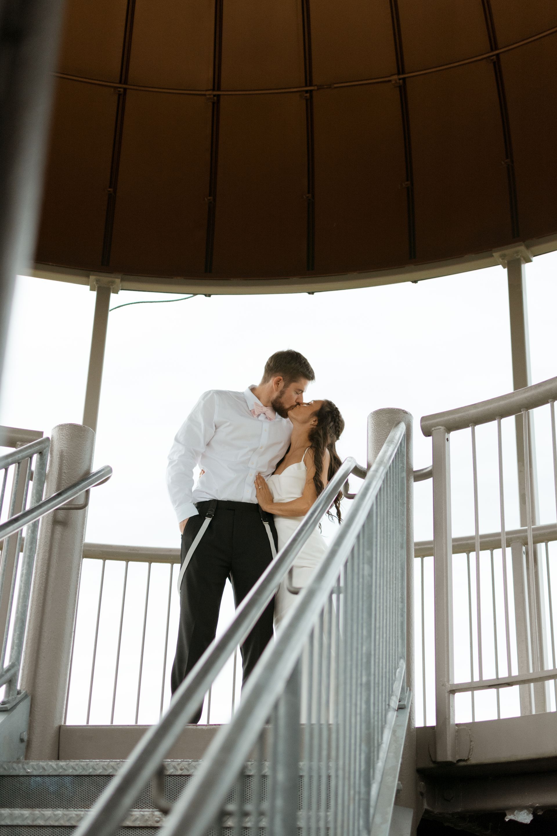 A bride and groom are kissing on a set of stairs.