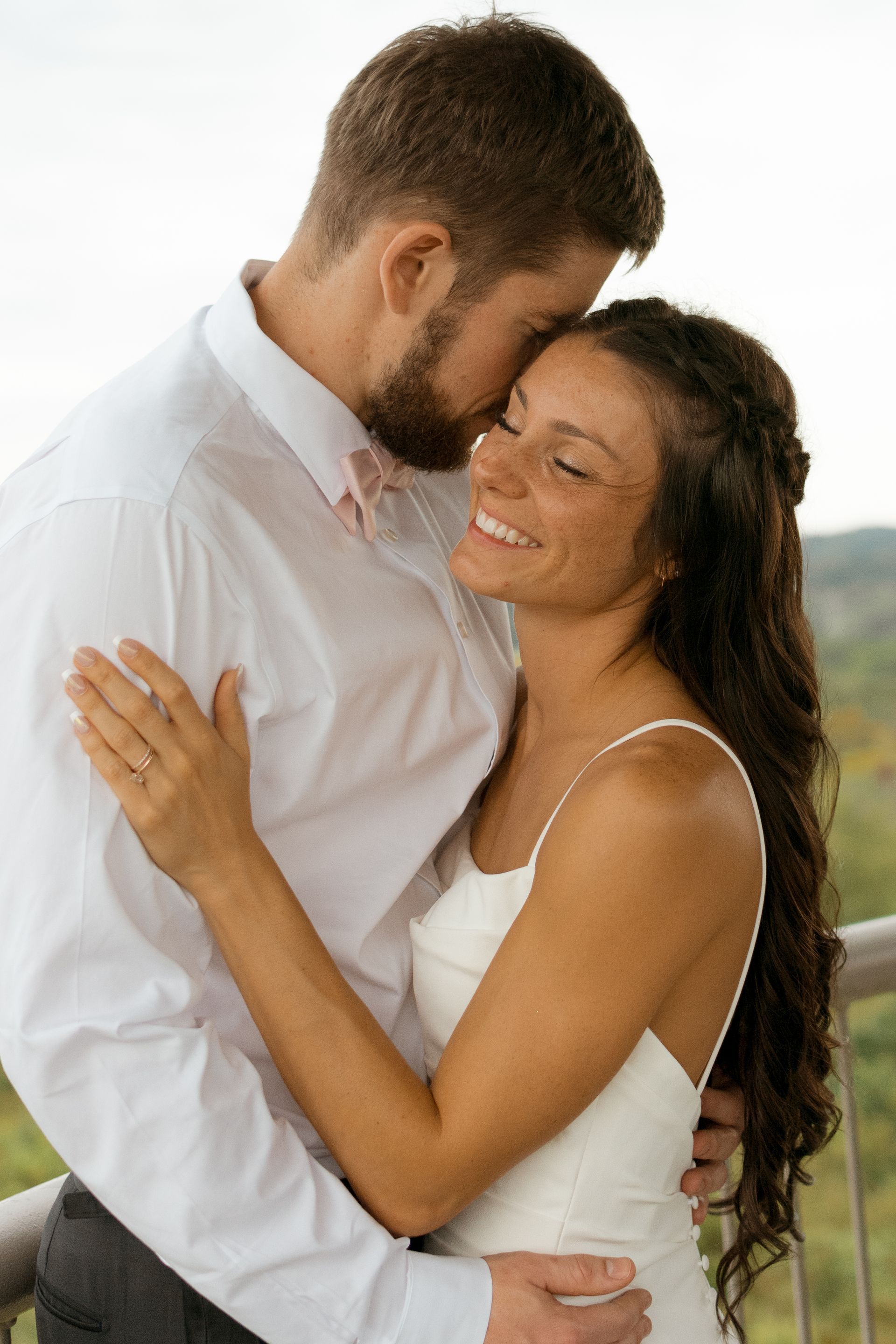 A bride and groom are hugging each other on a balcony.