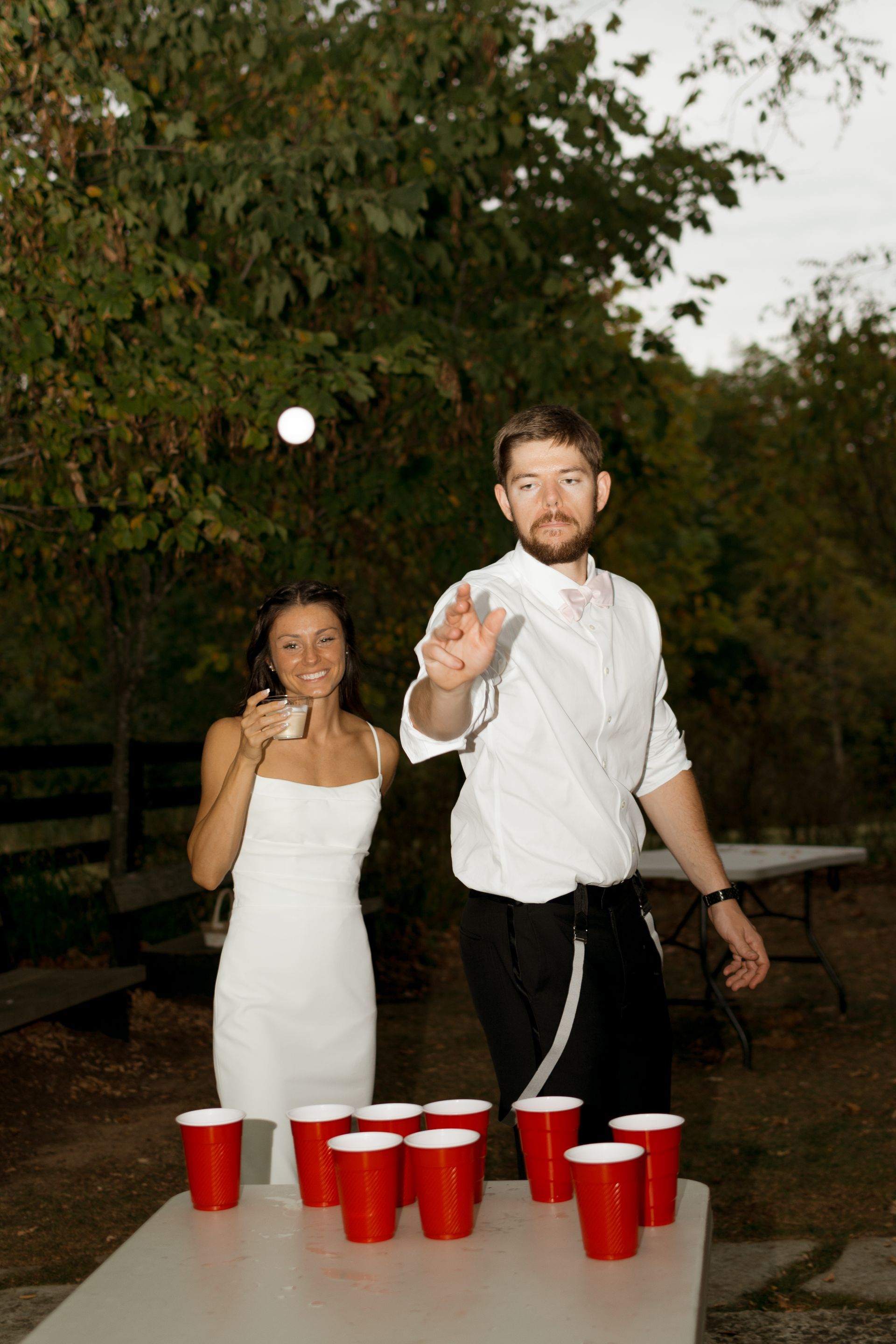 A man and a woman are playing beer pong on a table with red cups.