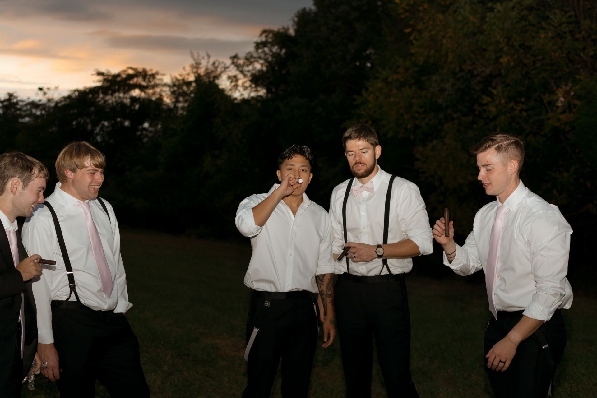 A group of men in suits and suspenders are standing in a field.