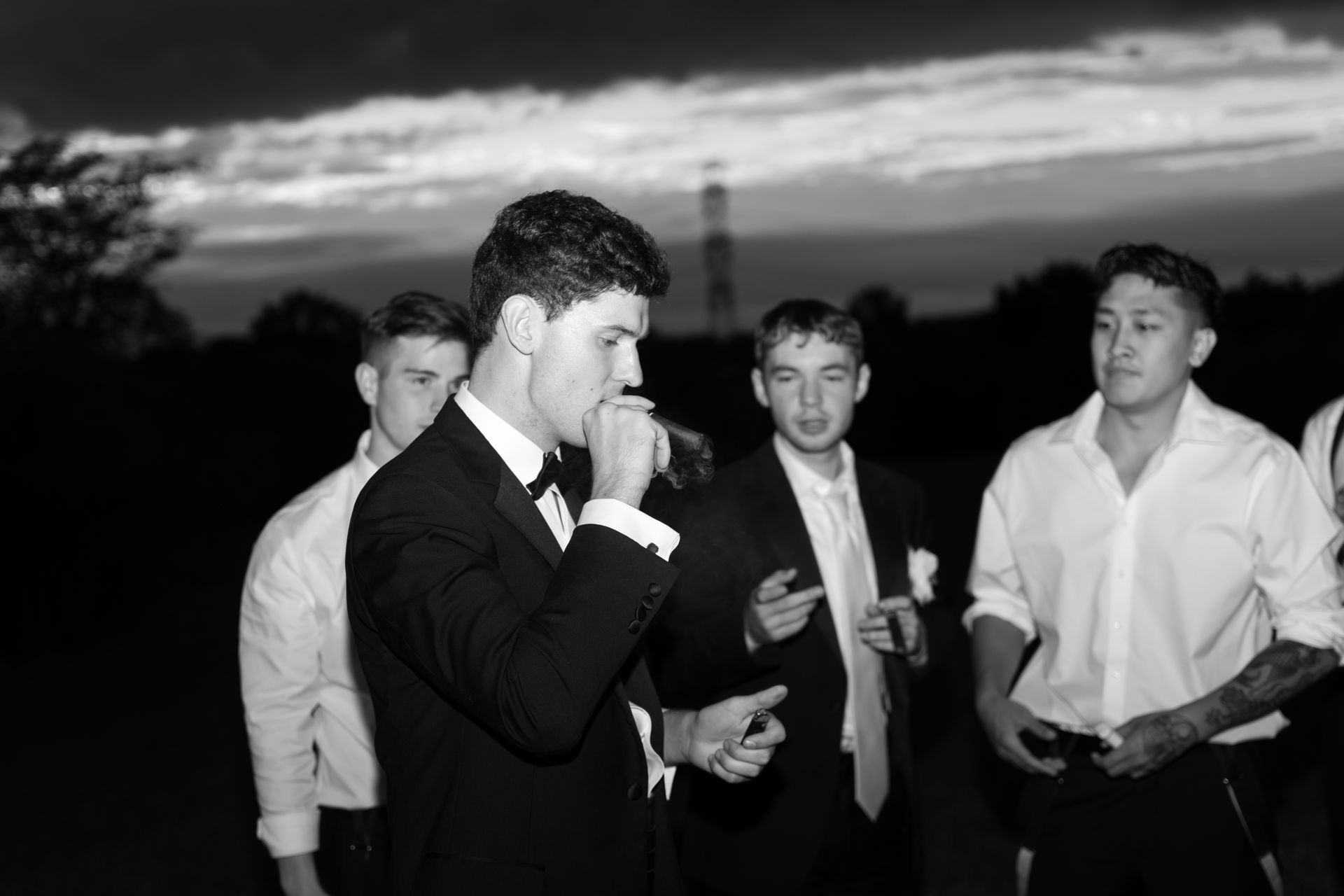 A groom lighting a cigar surrounded by his groomsmen