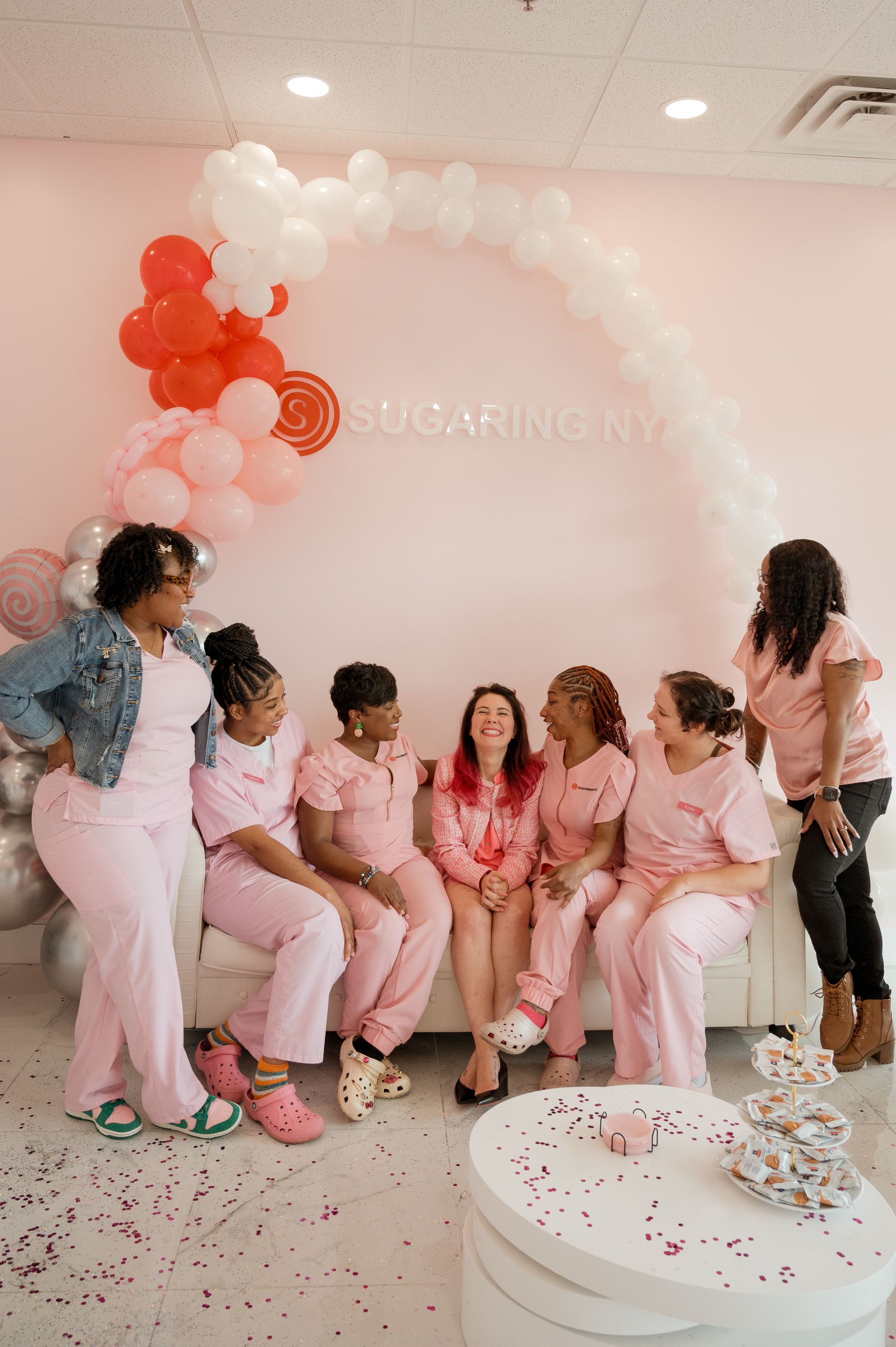 A group of women in pink scrubs are sitting on a couch.