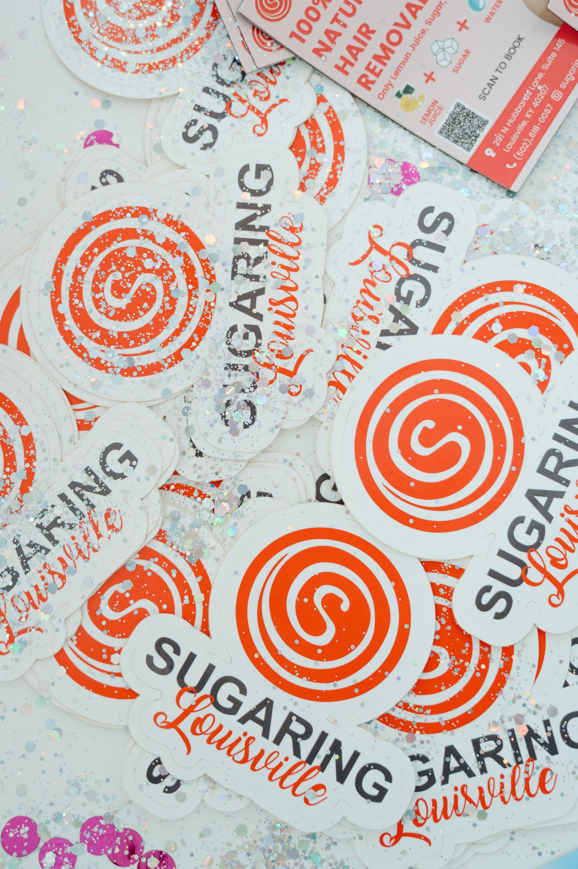 A bunch of sugaring louisville stickers on a table