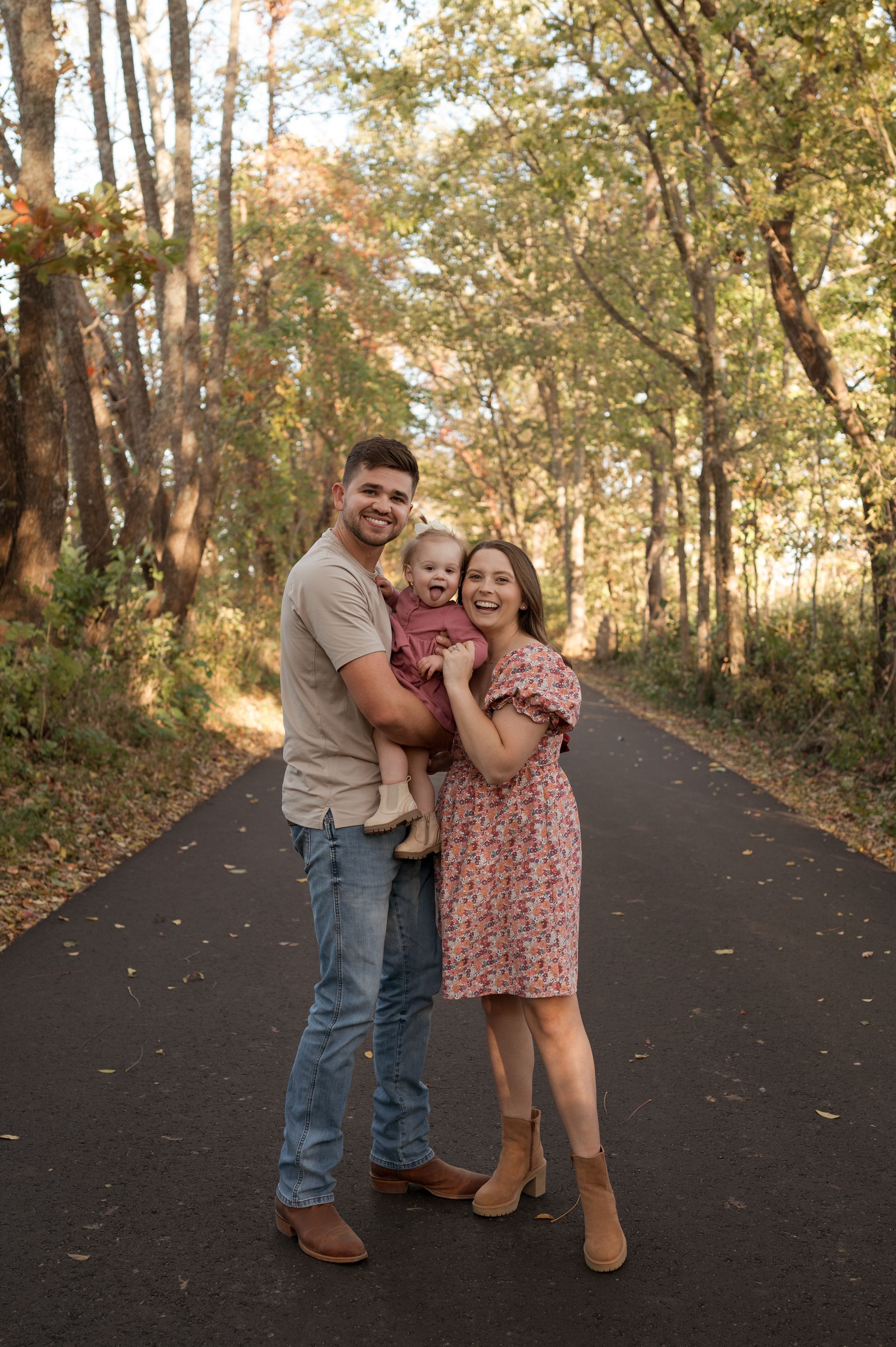 A family is posing for a picture on a road in the woods.