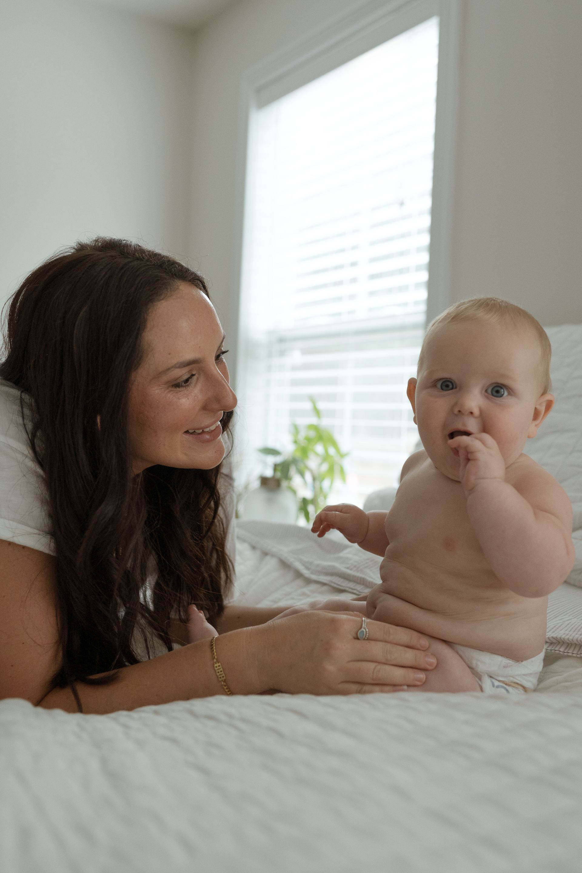 A woman is laying on a bed with a baby.