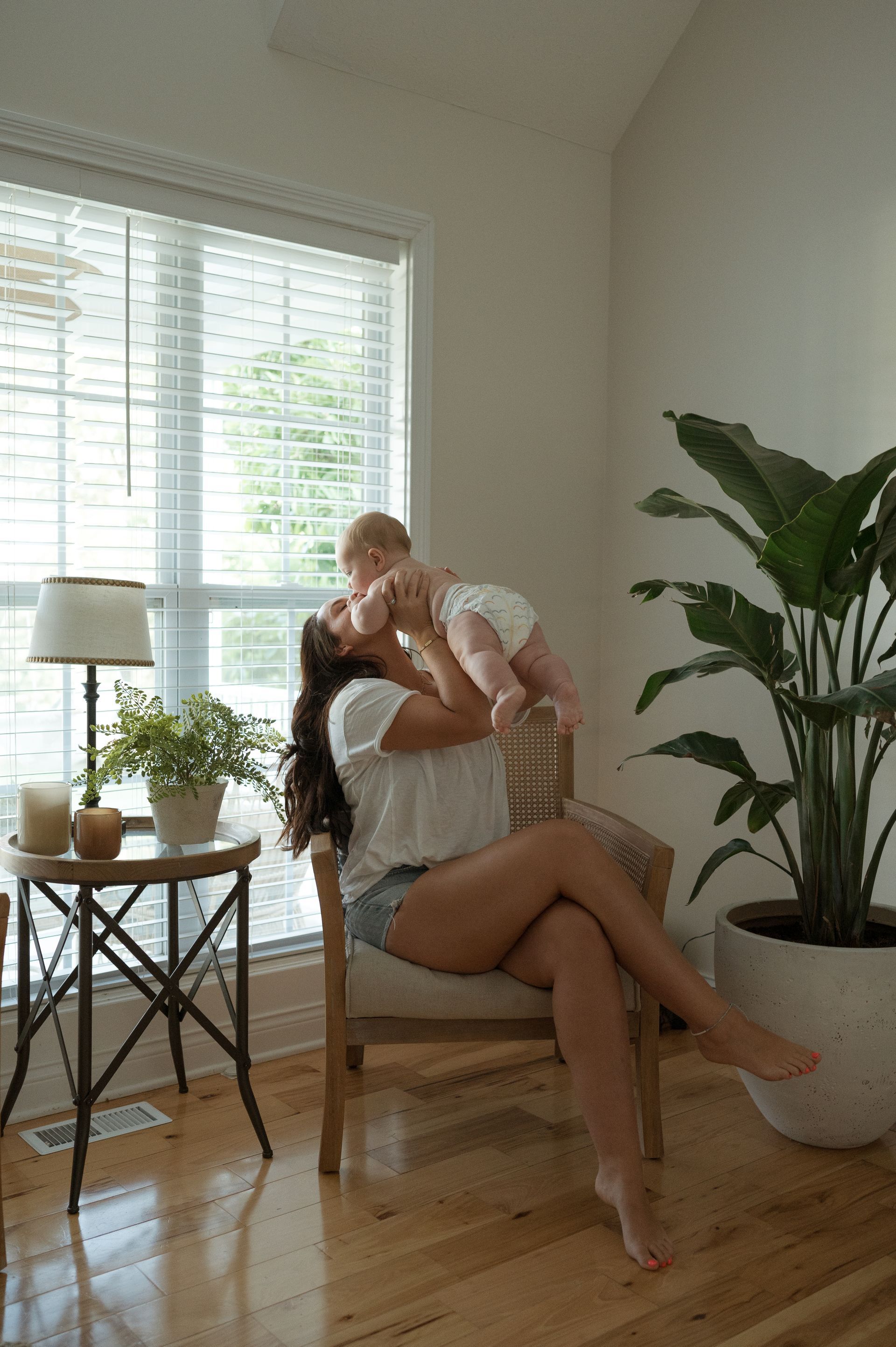 A woman is sitting in a chair holding a baby in her arms.