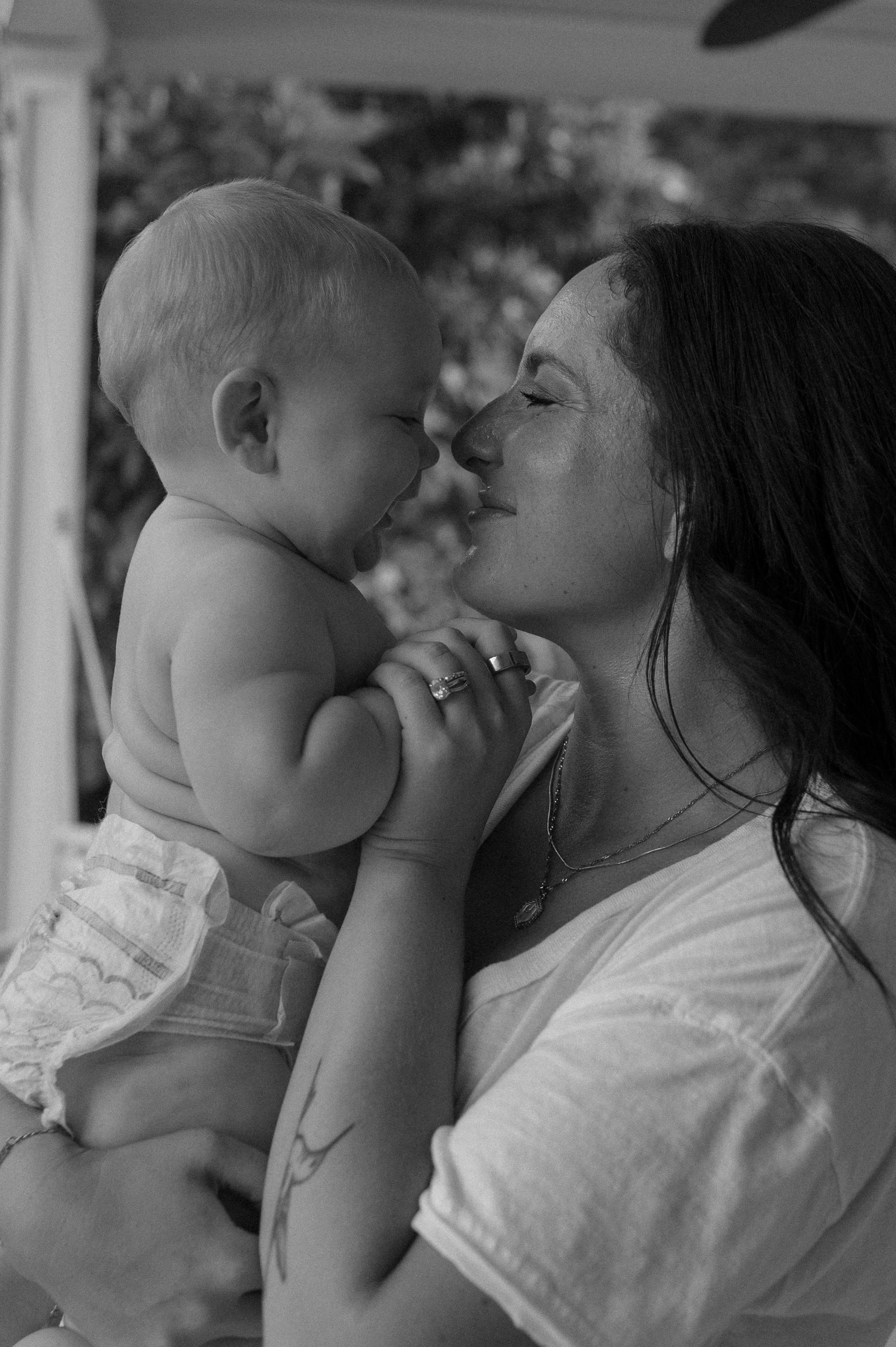A woman is holding a baby in her arms and kissing it on the cheek.