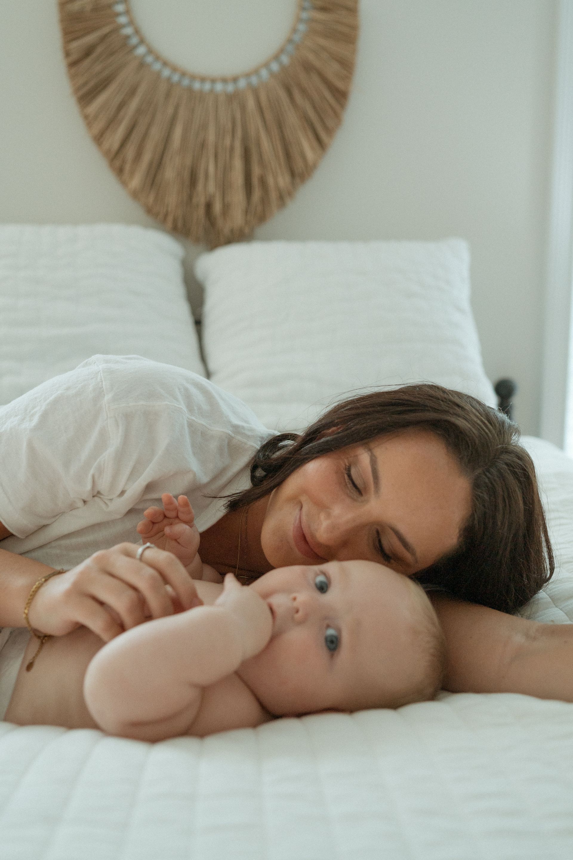 A woman is laying on a bed with a baby.