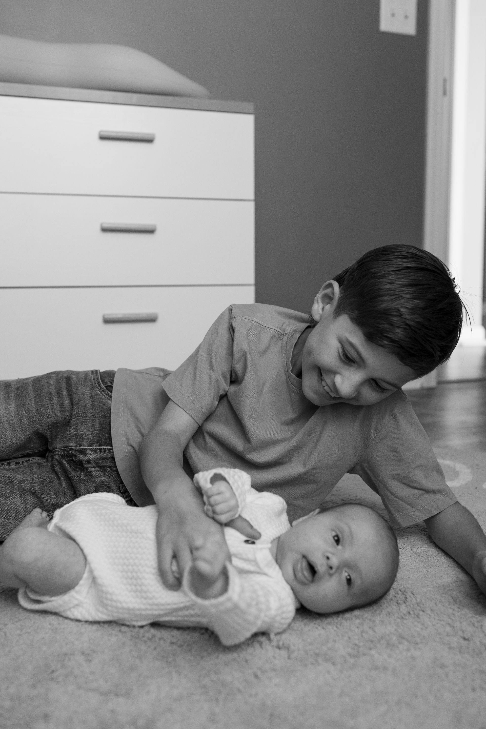 A boy is playing with a baby on the floor
