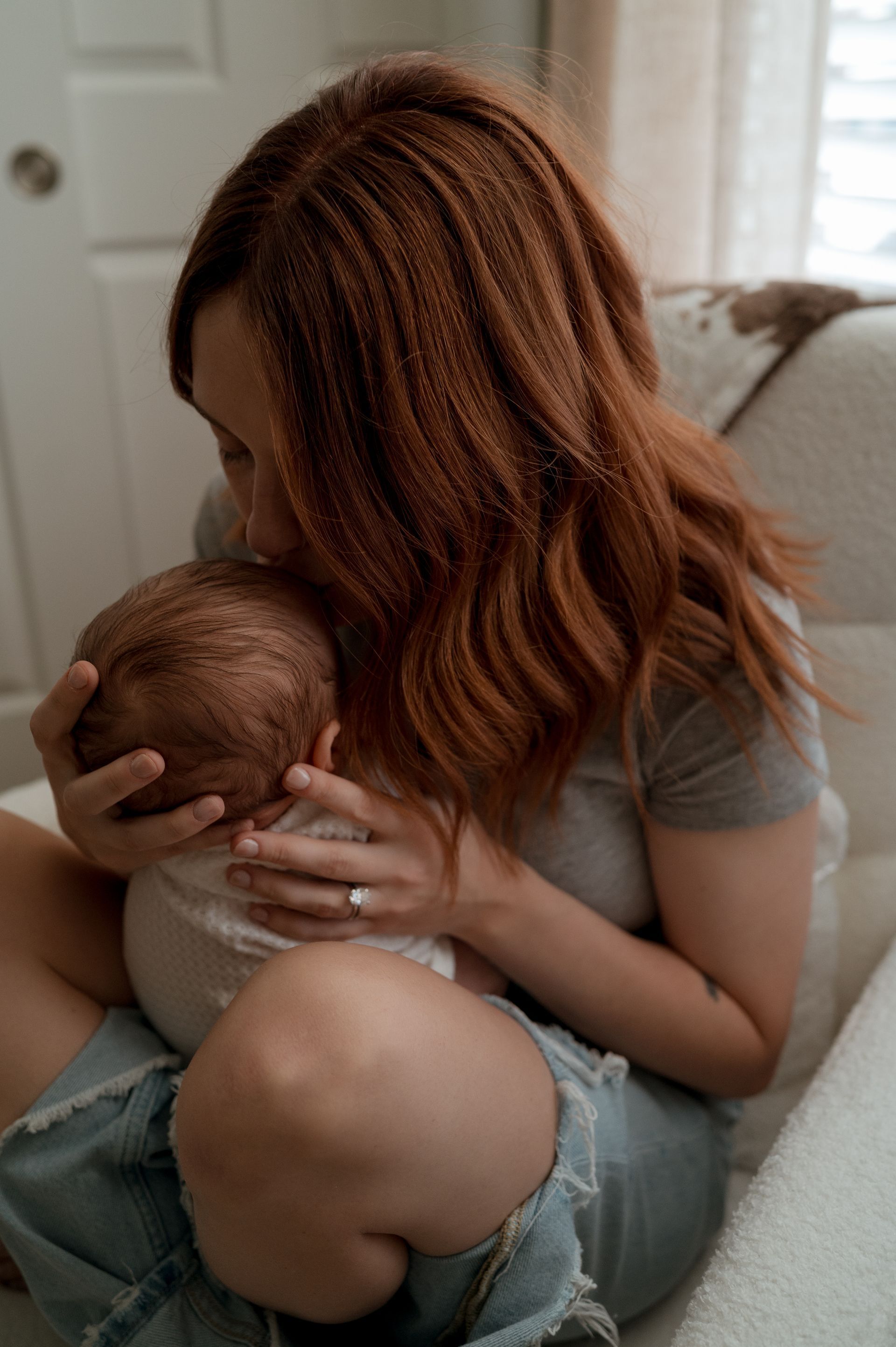 A woman is holding a baby in her arms while sitting on a couch.