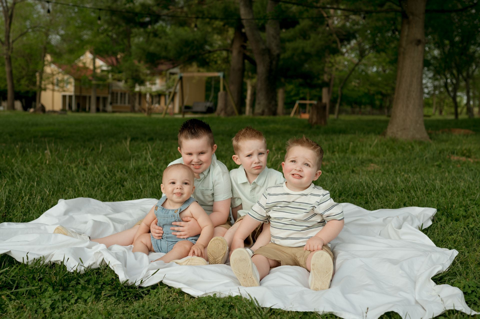 A group of children are sitting on a blanket in the grass.