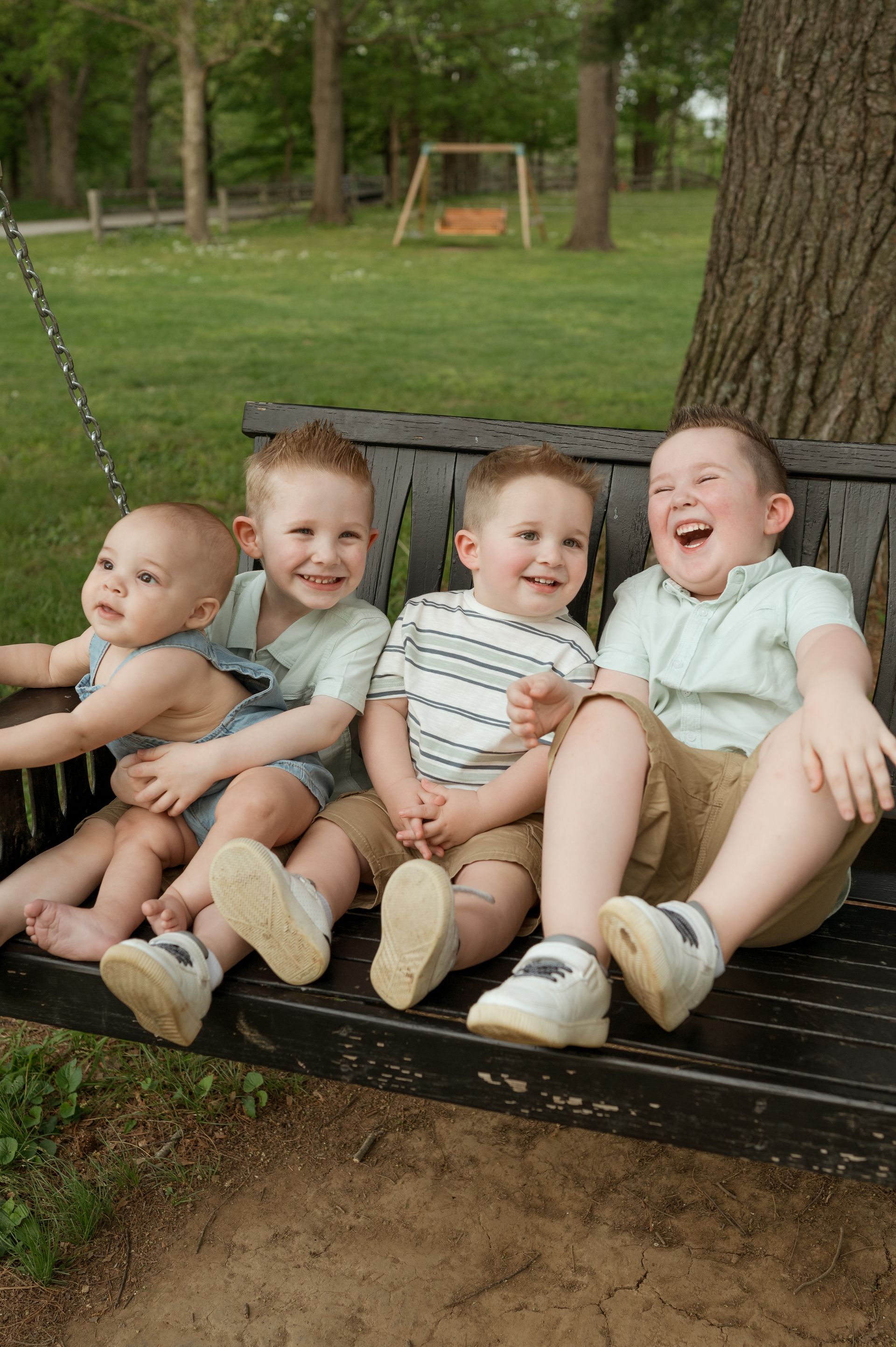 Four young boys are sitting on a porch swing