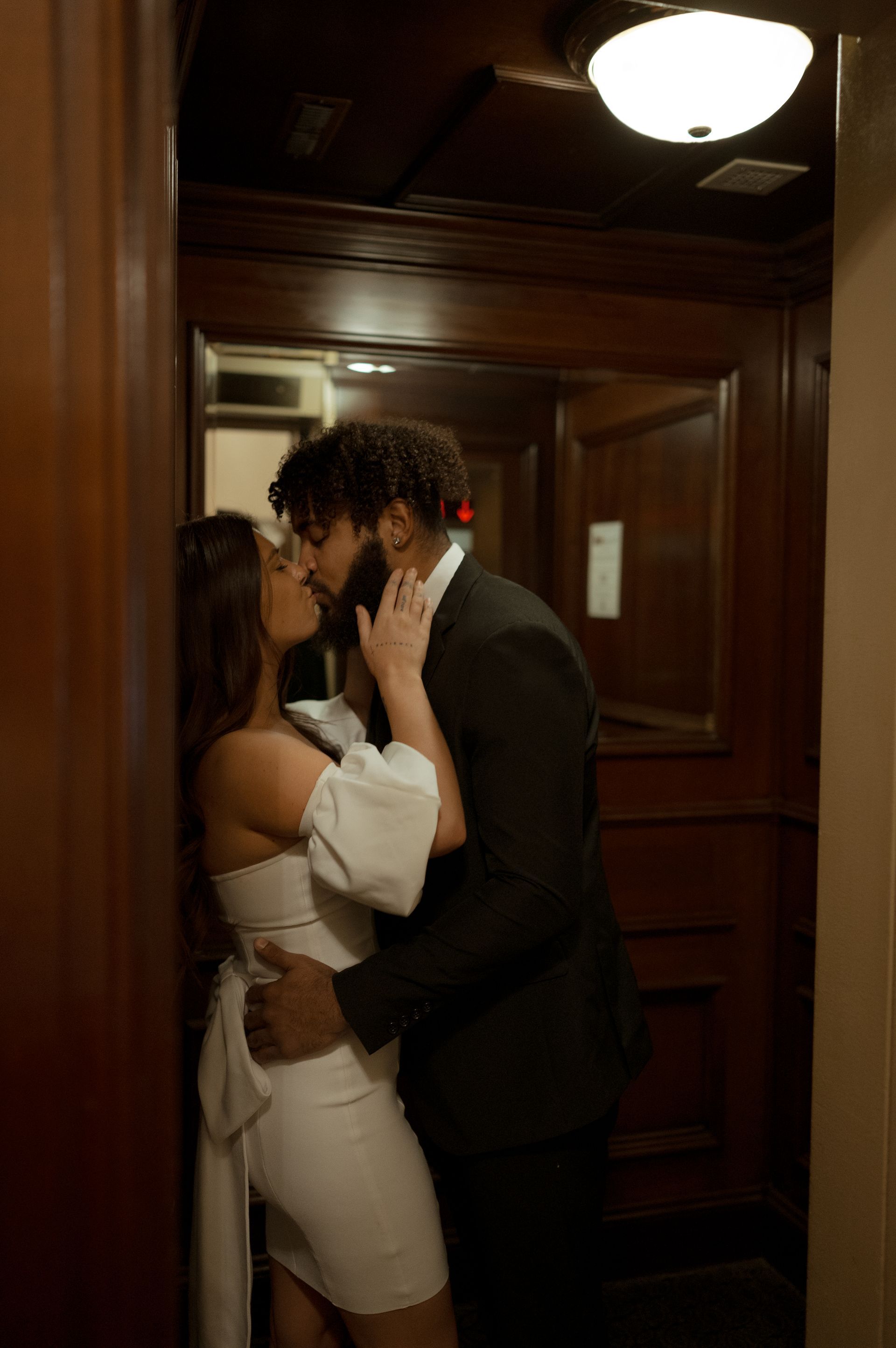 A man and a woman are kissing in an elevator.