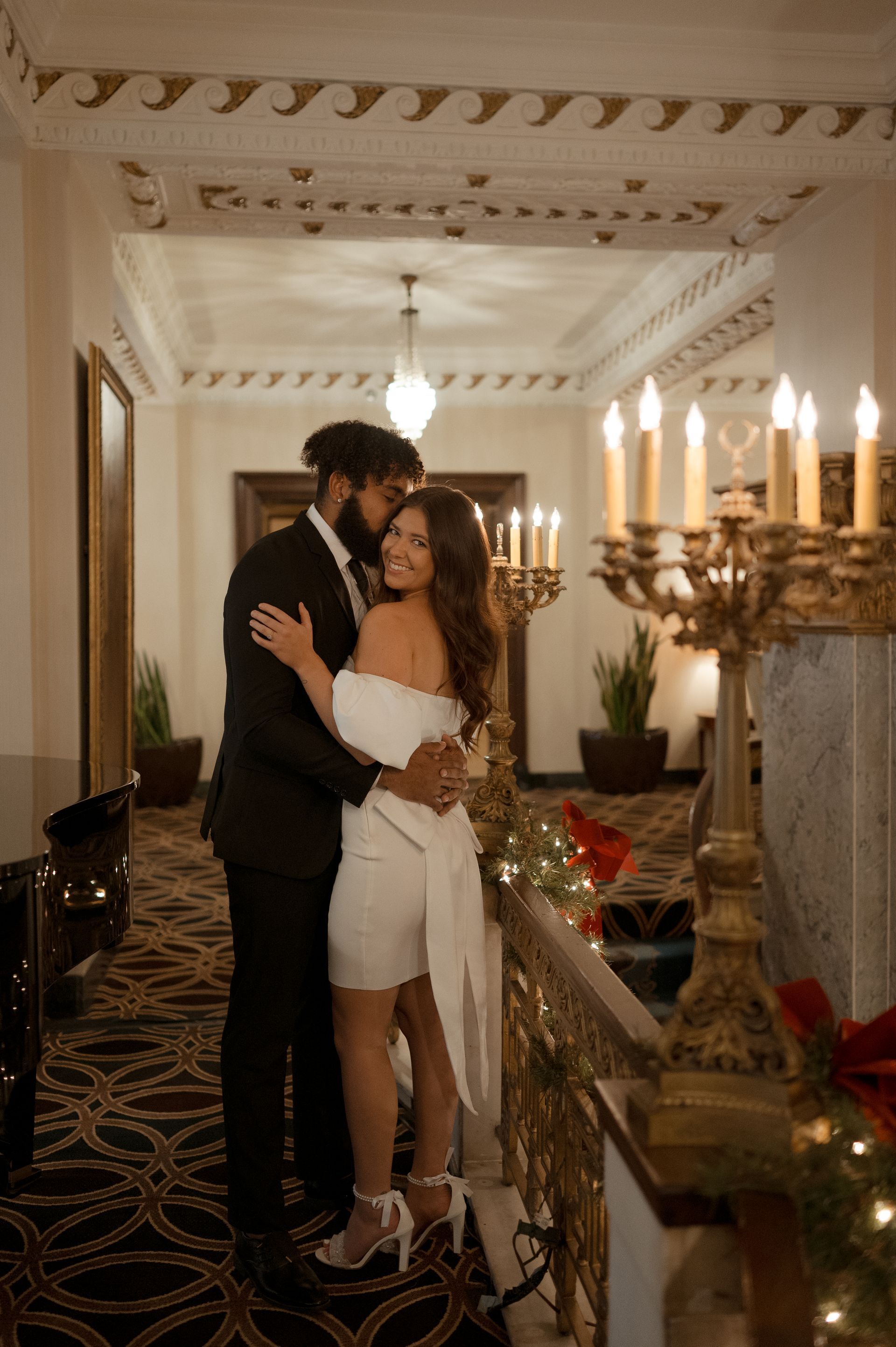 A man and woman are hugging in a hallway with candles.