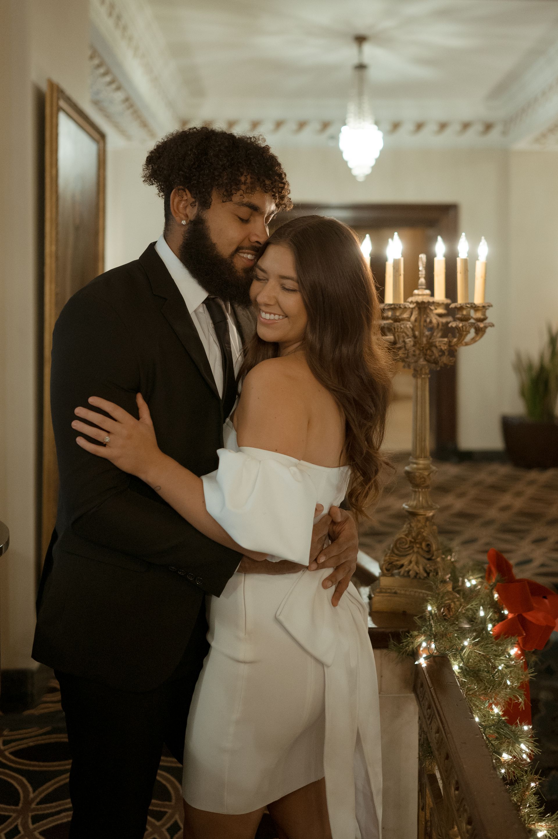 A man in a suit and tie is hugging a woman in a white dress.