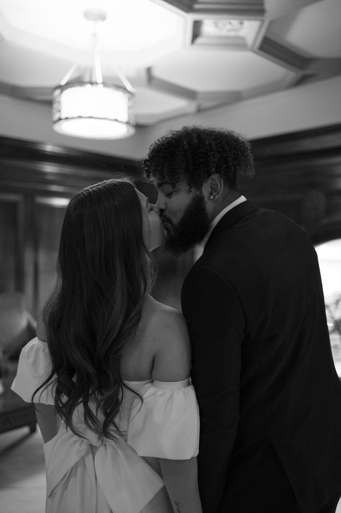 A bride and groom are kissing in a black and white photo.