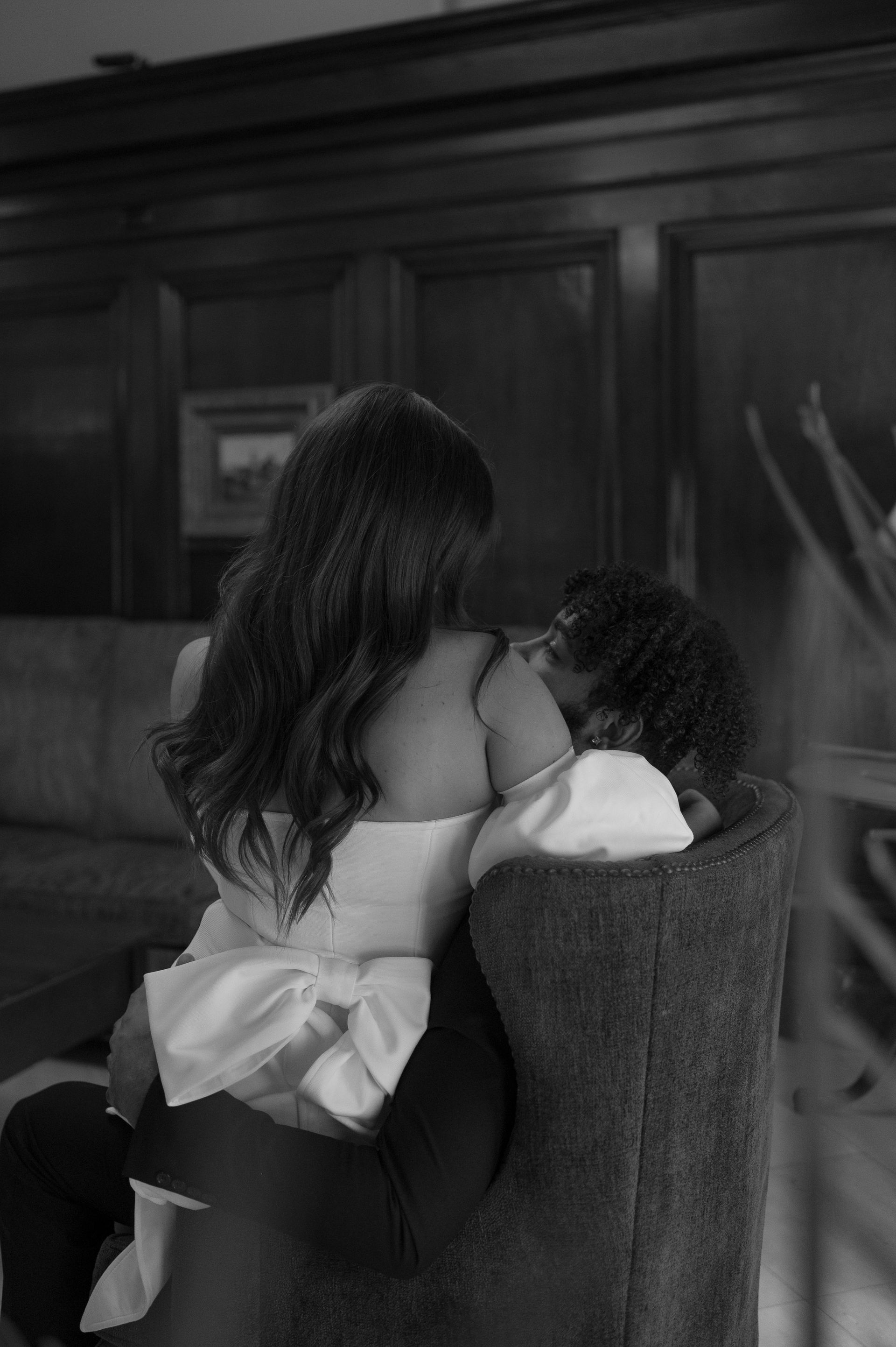 A black and white photo of a woman sitting in a chair holding a baby.