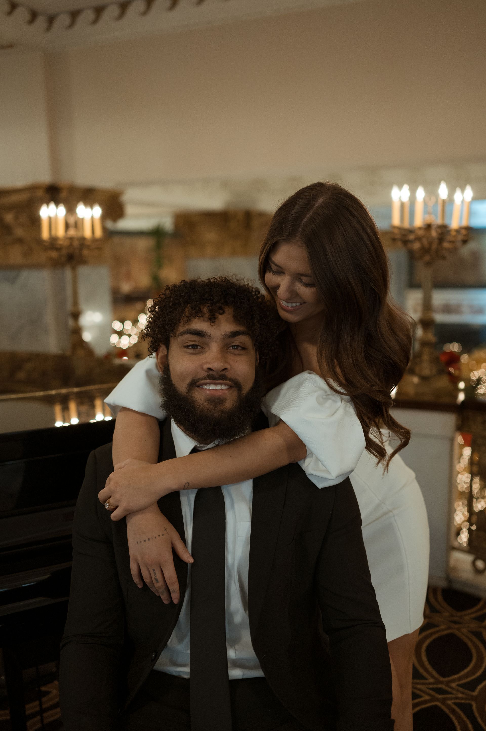 A woman is hugging a man in a suit and tie.