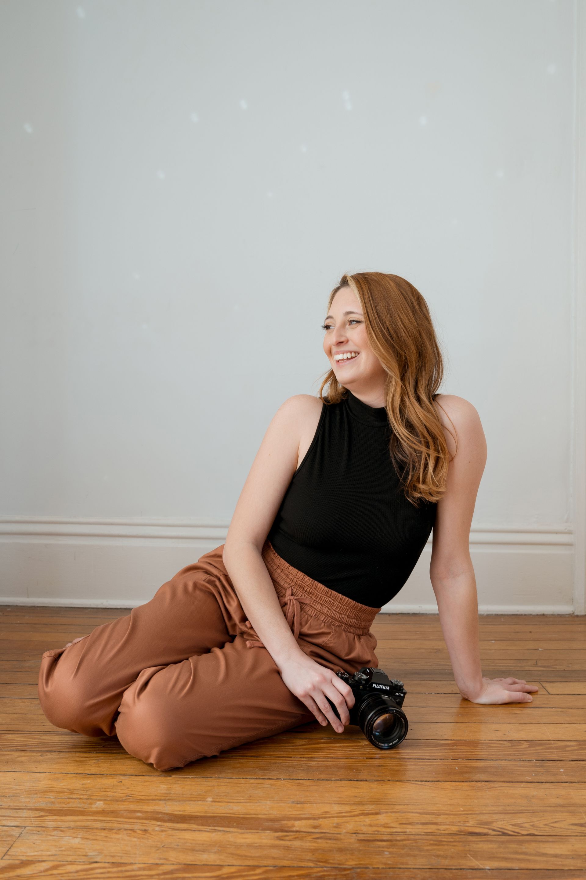 A woman is sitting on the floor holding a camera.