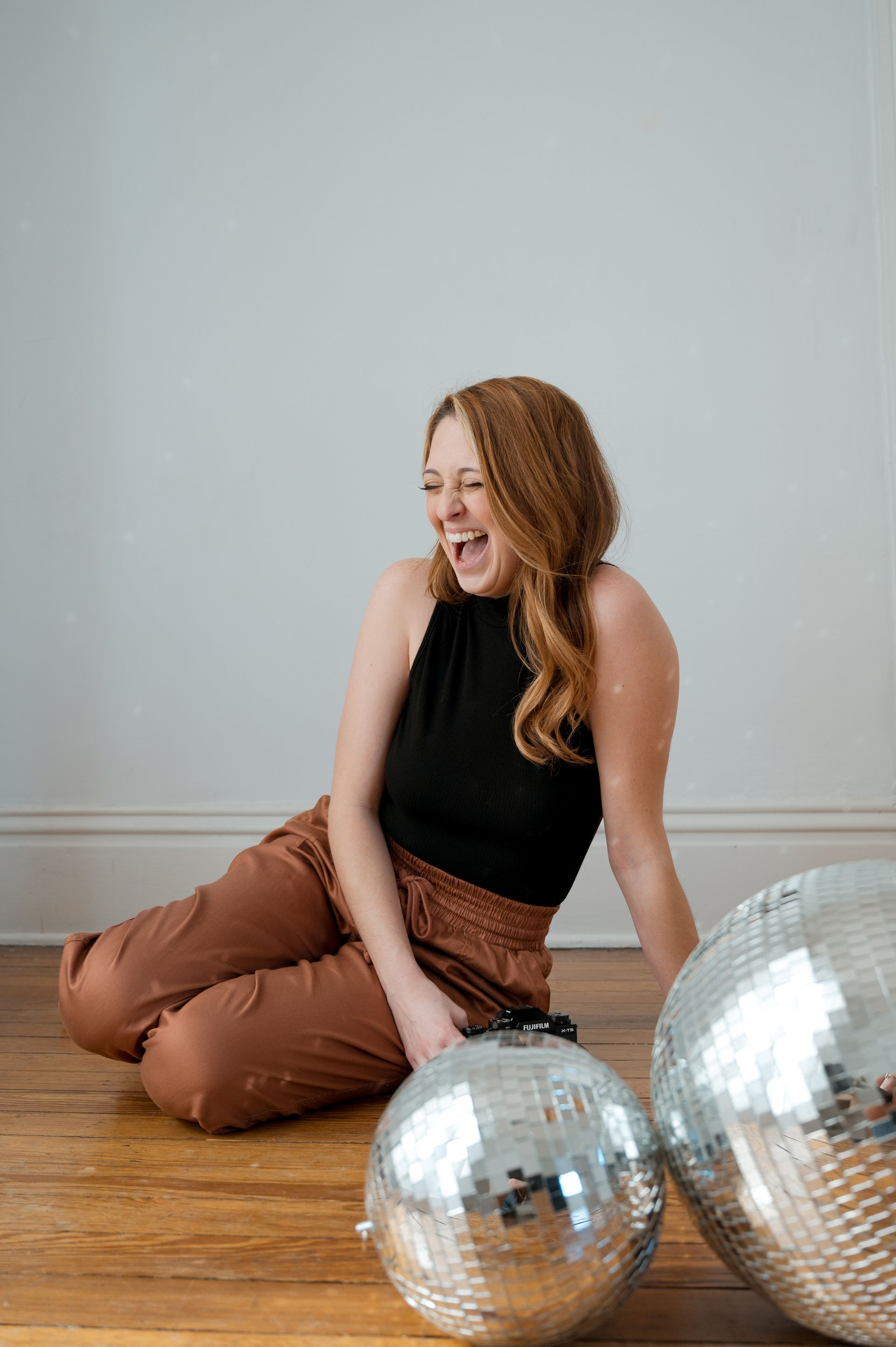 A woman is sitting on the floor next to two disco balls.
