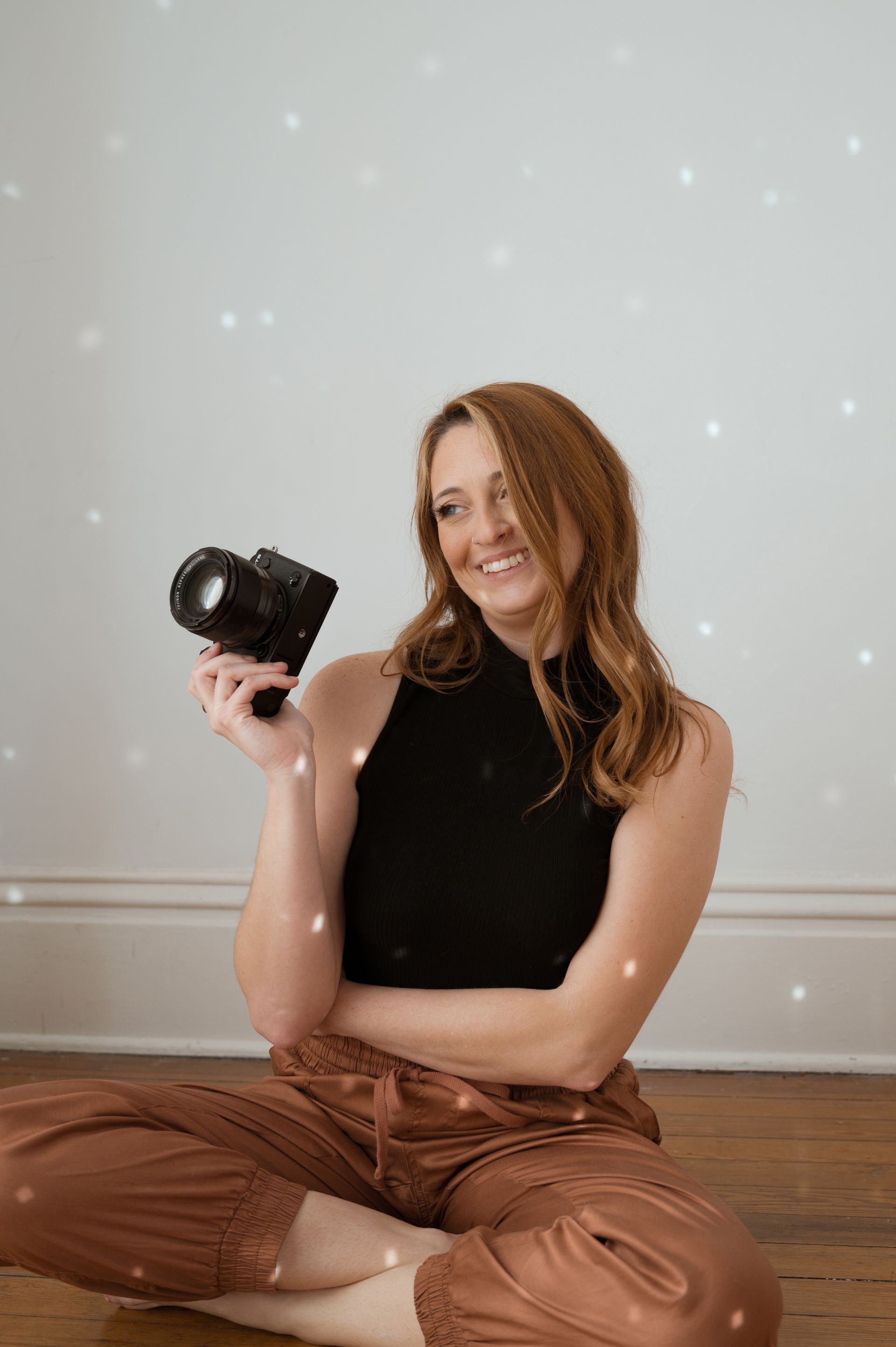 A woman is sitting on the floor holding a camera.