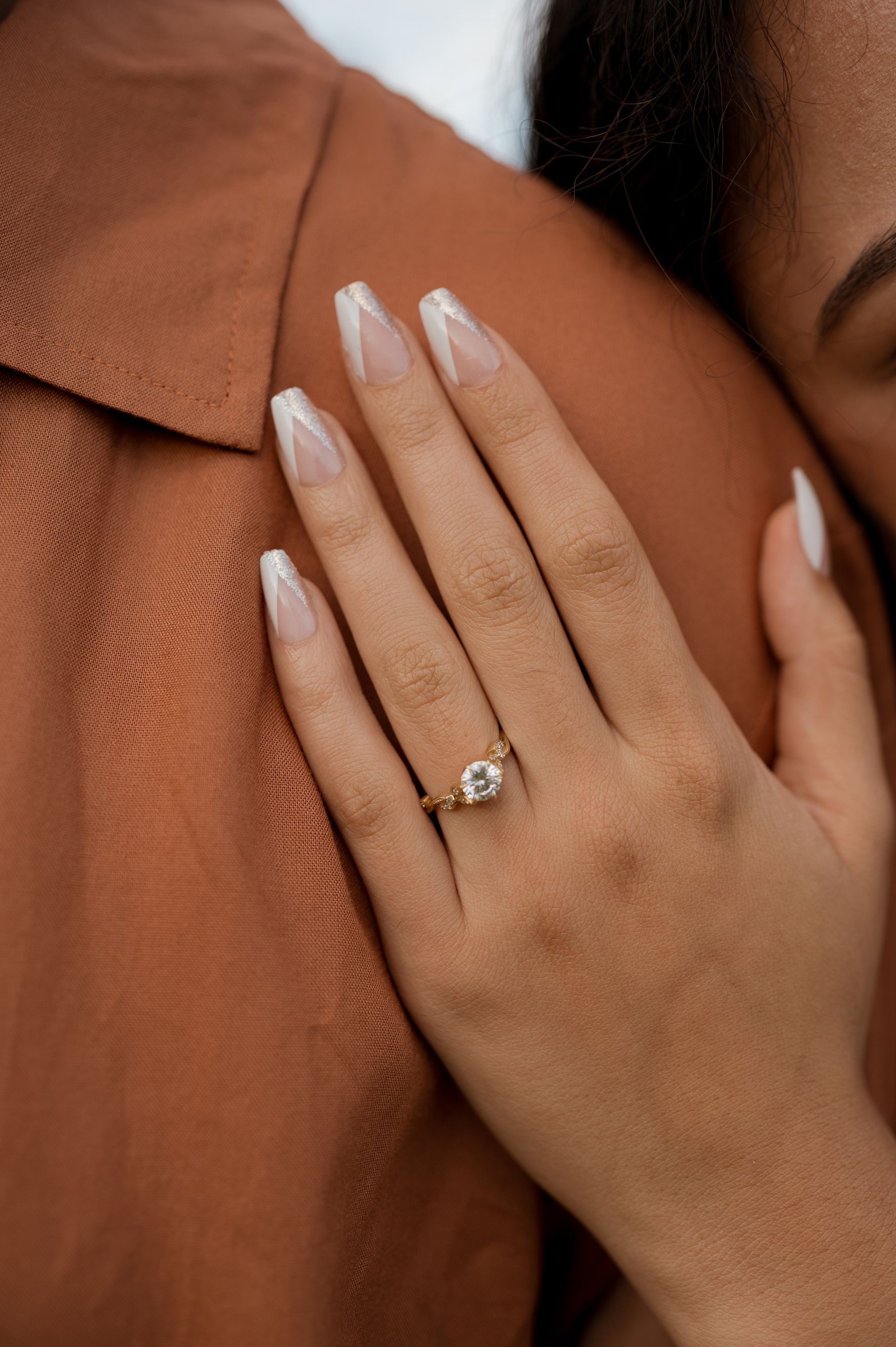 a close up of a woman hand on a mans chest with her engagement ring in focus
