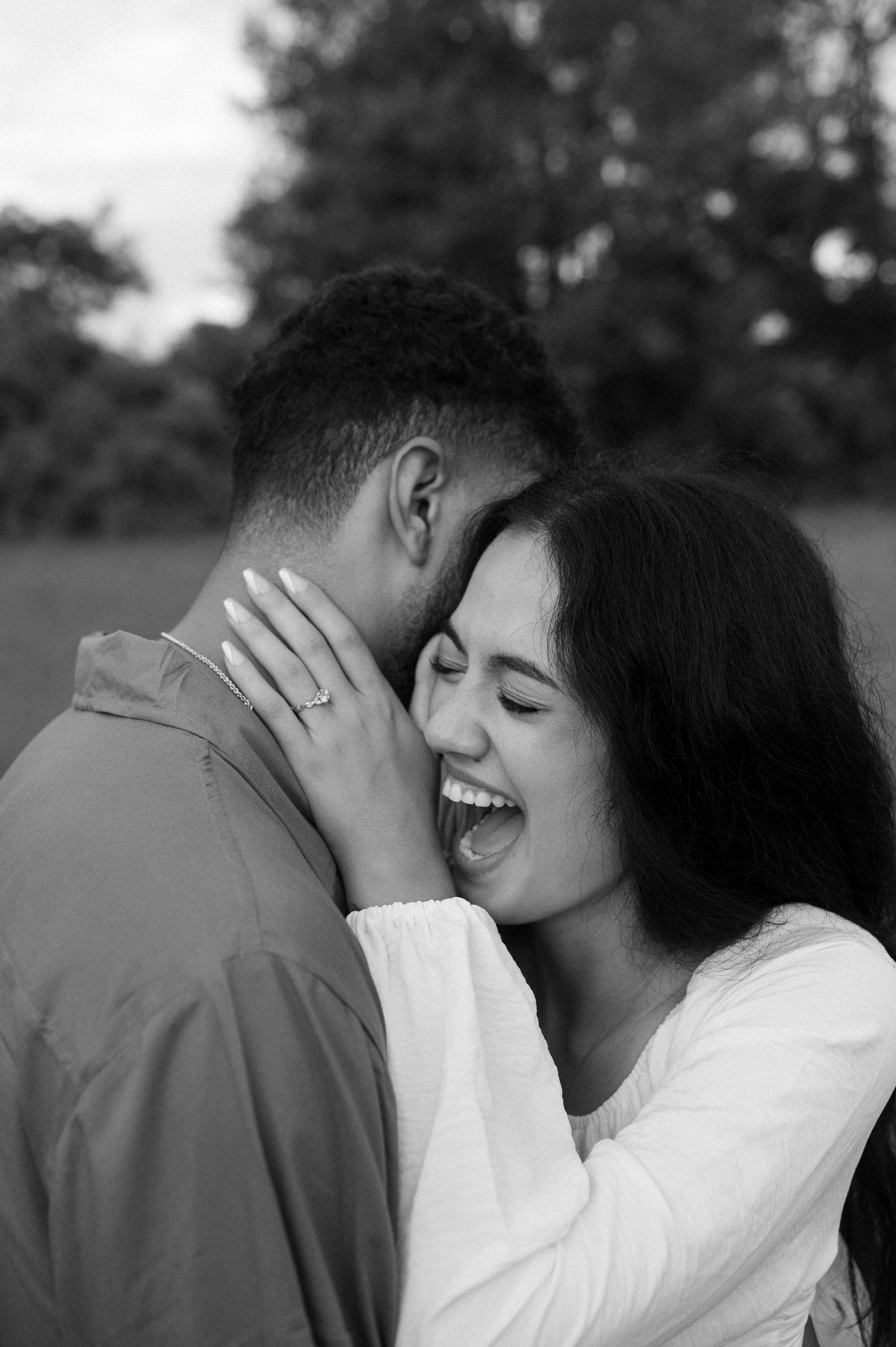 A black and white photo of a man and woman hugging each other . the woman is wearing a ring on her finger.