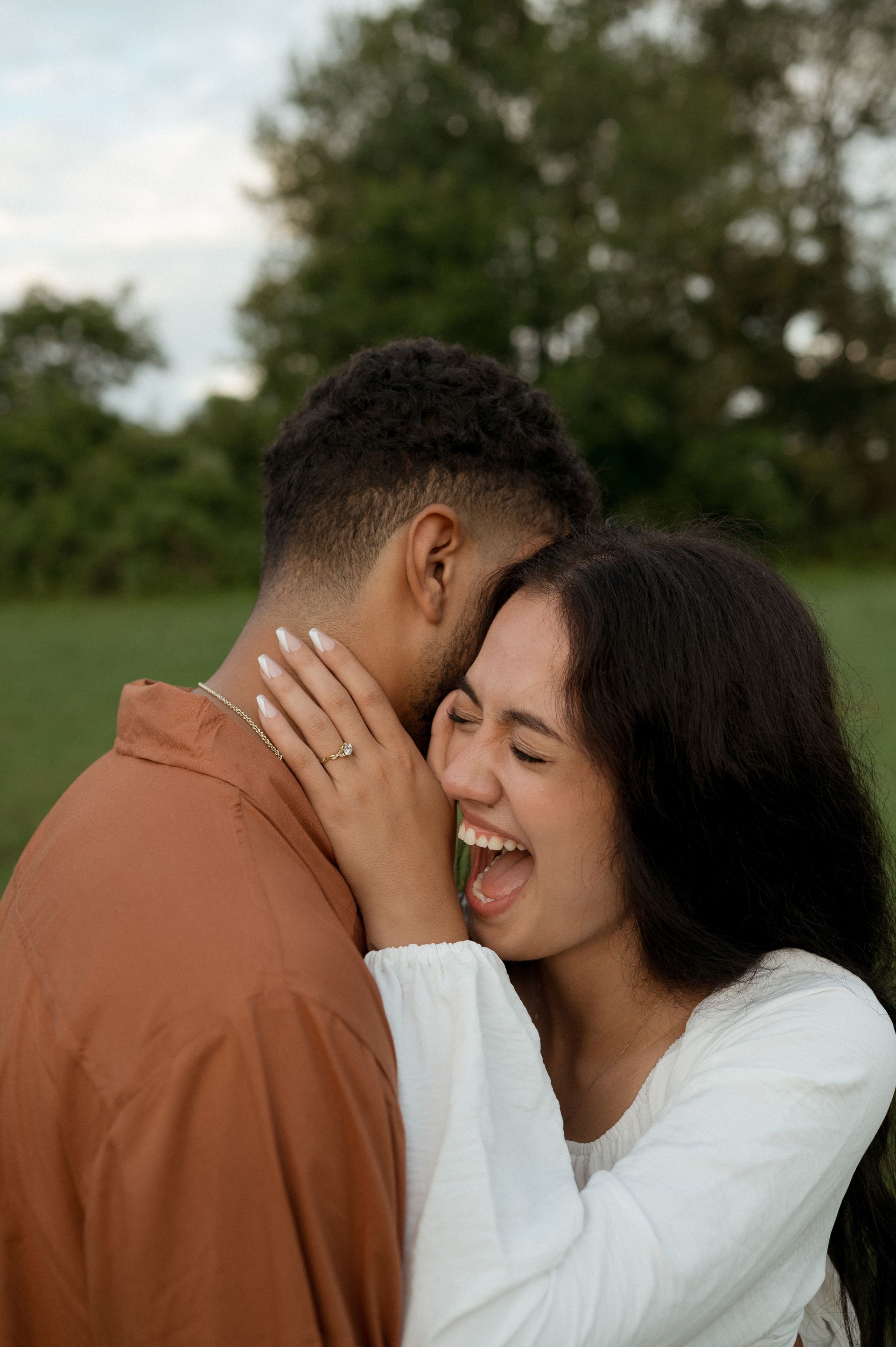 A woman is sticking her tongue out while hugging a man.