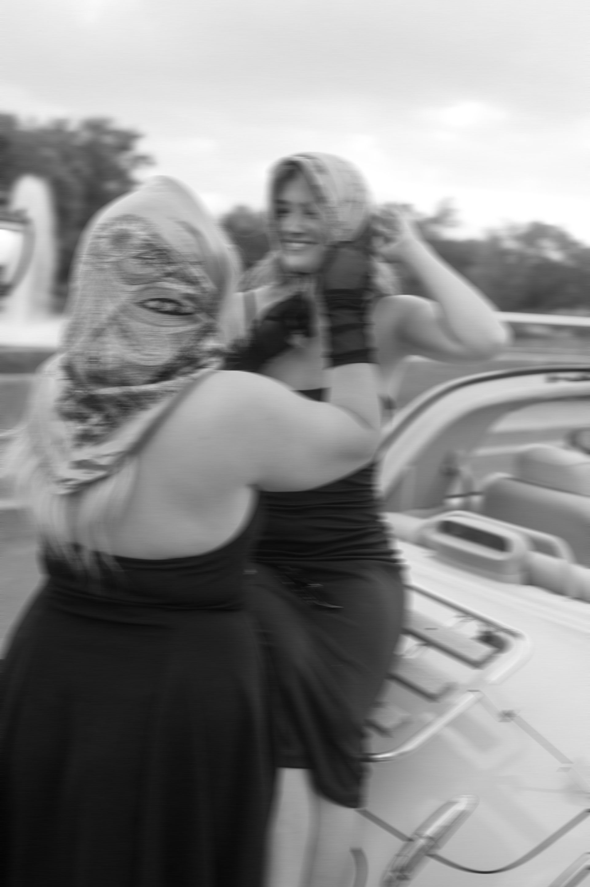 A black and white photo of two women standing next to a car