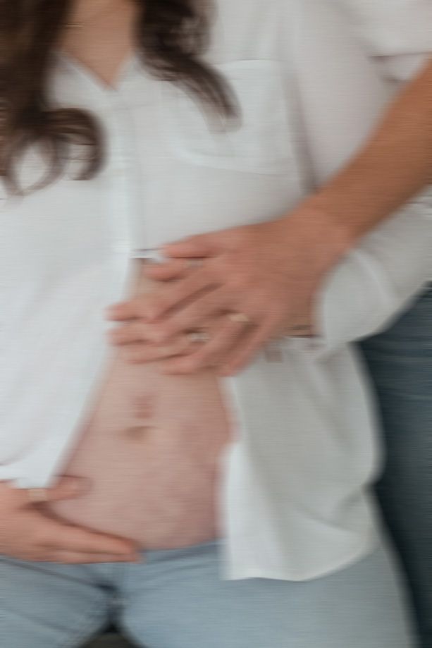 A man is holding a pregnant woman 's belly.