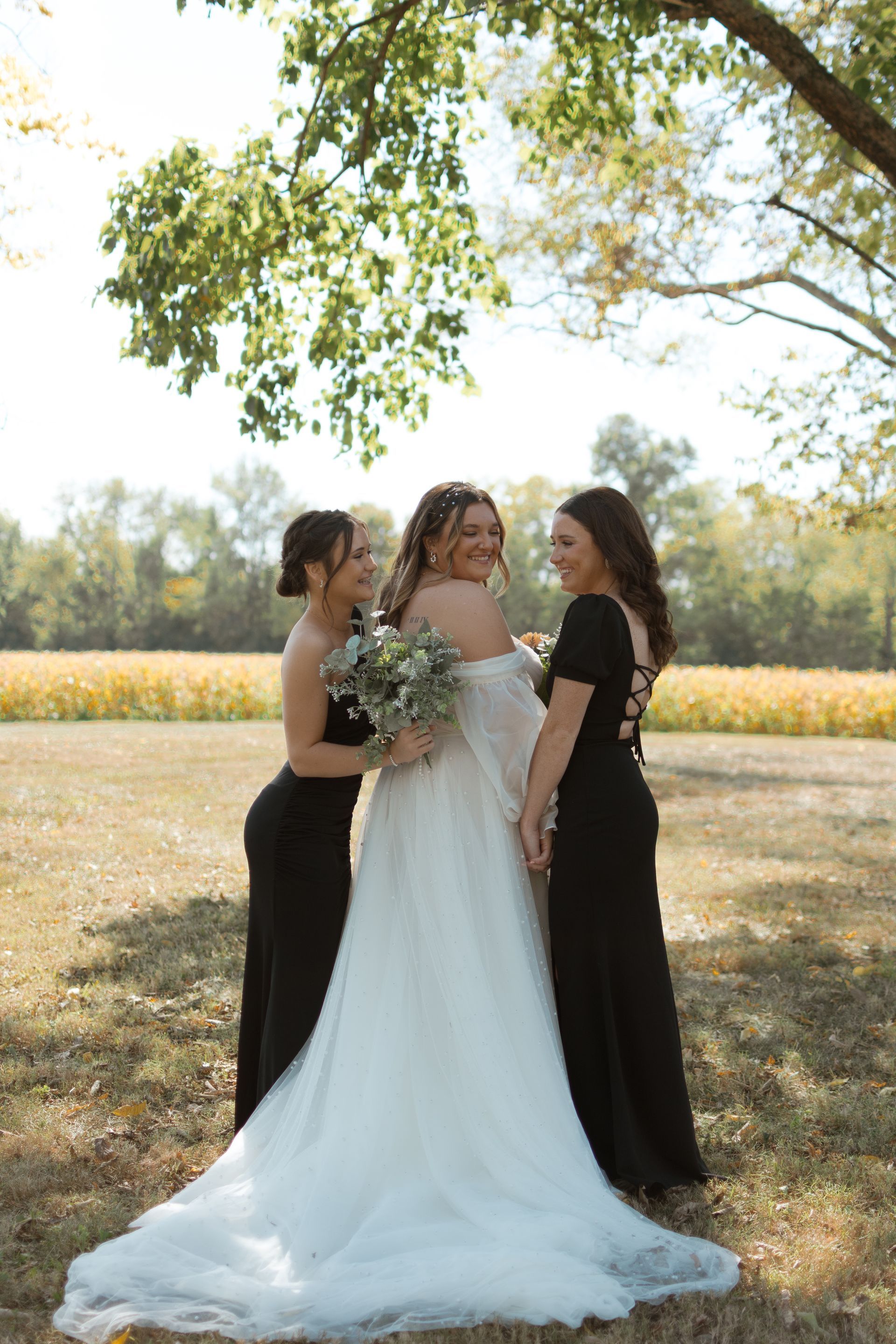 A bride and her bridesmaids are posing for a picture in a field.