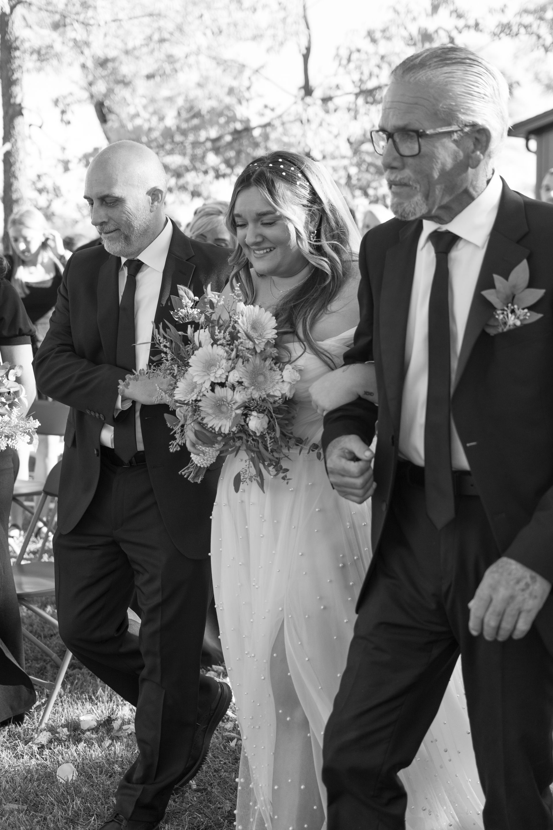 A bride and her father are walking down the aisle at a wedding.