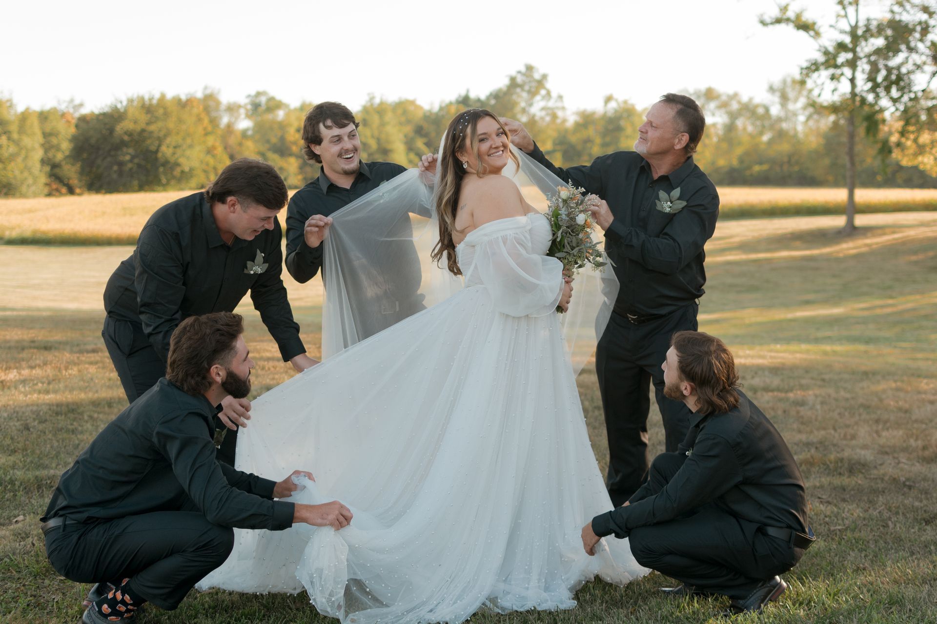 A group of men are kneeling around a bride in a wedding dress.