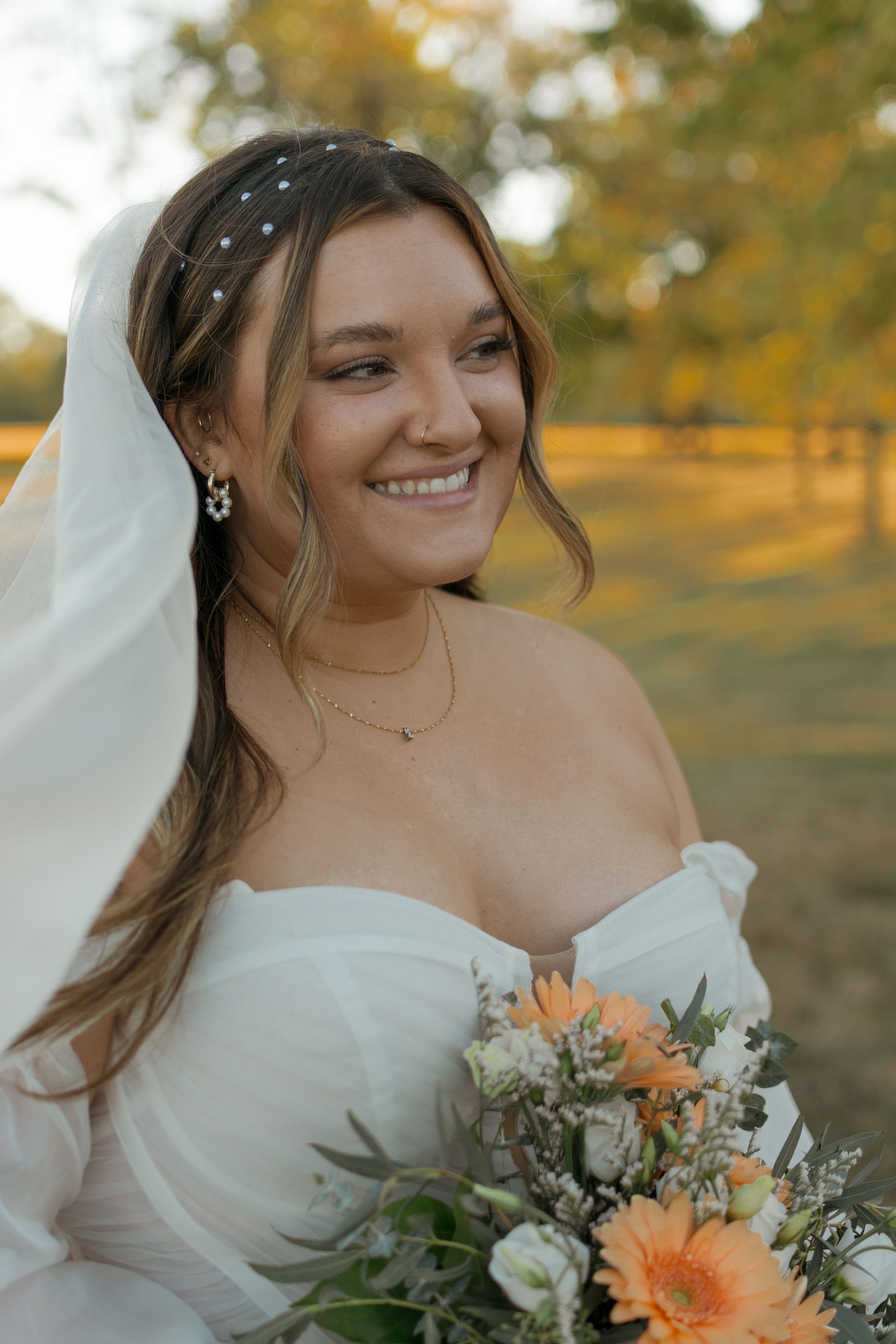 A bride in a white dress is holding a bouquet of flowers and smiling.