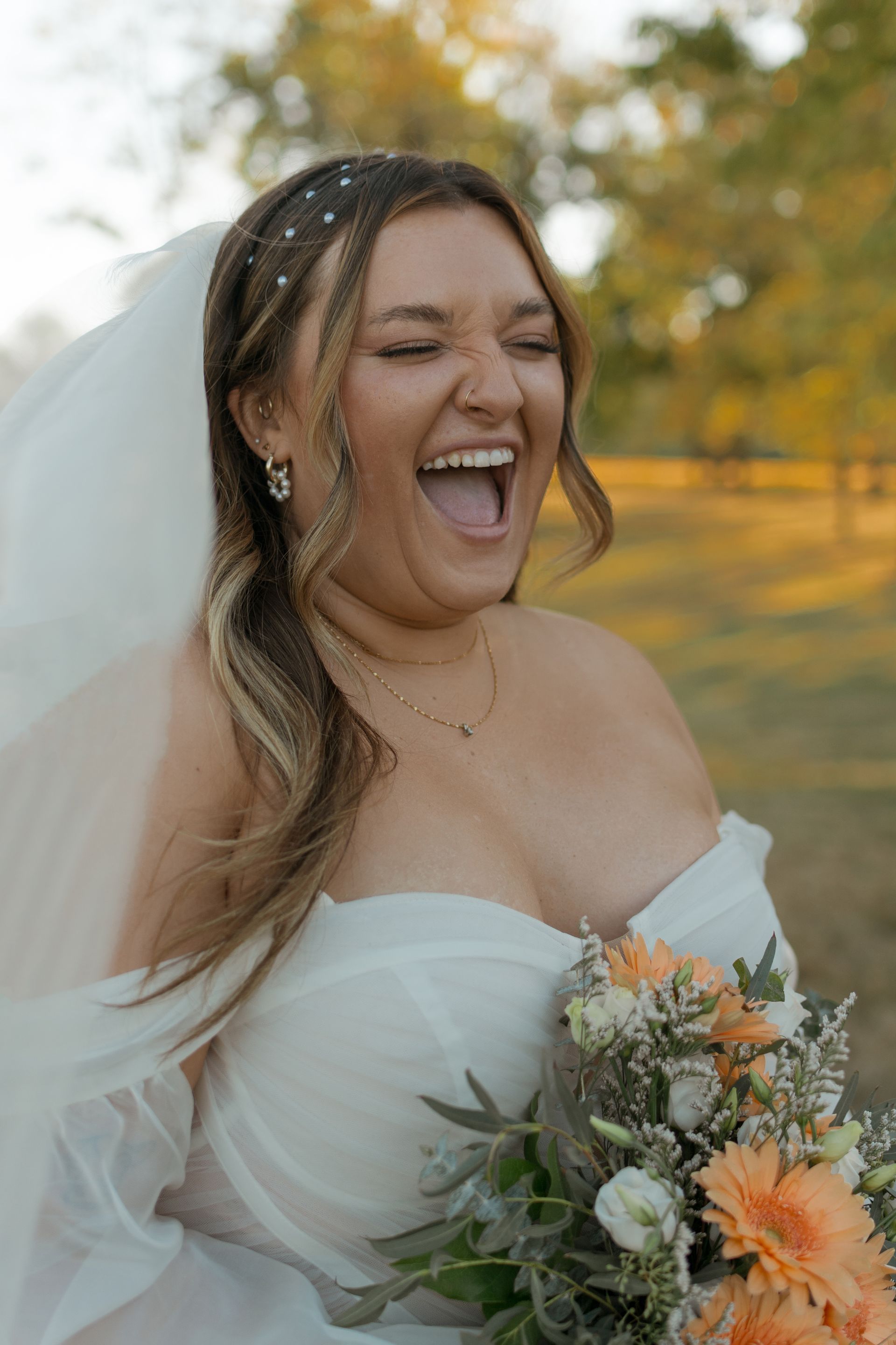 A woman in a wedding dress is holding a bouquet of flowers and laughing.