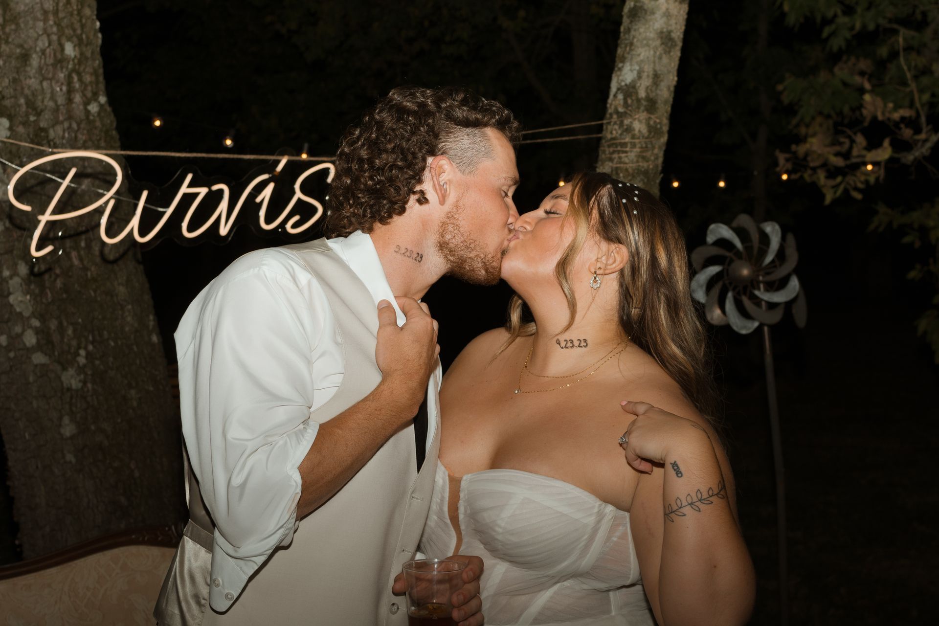 A bride and groom are kissing under a sign that says purvis.