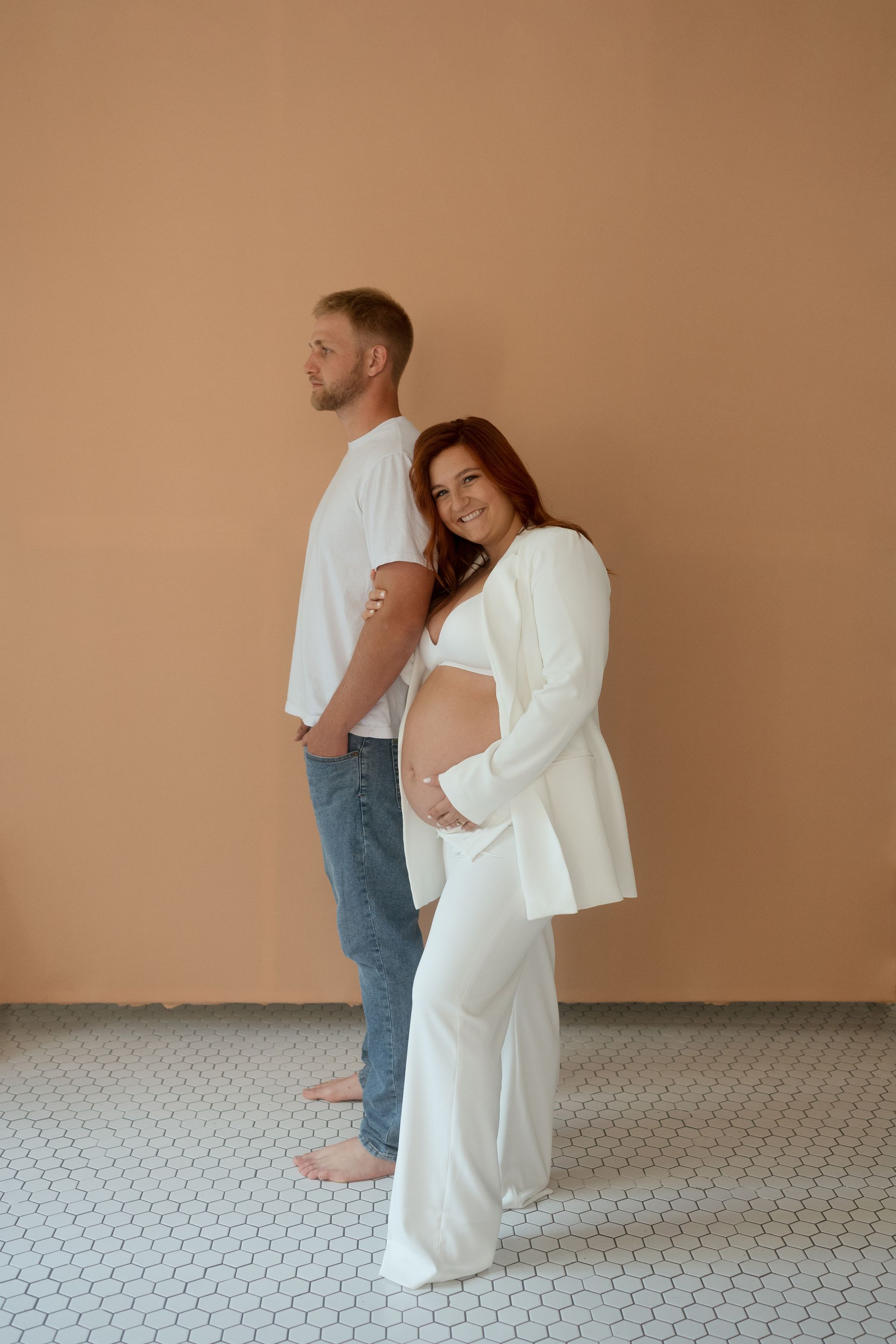 A man and a pregnant woman are standing next to each other in a room.