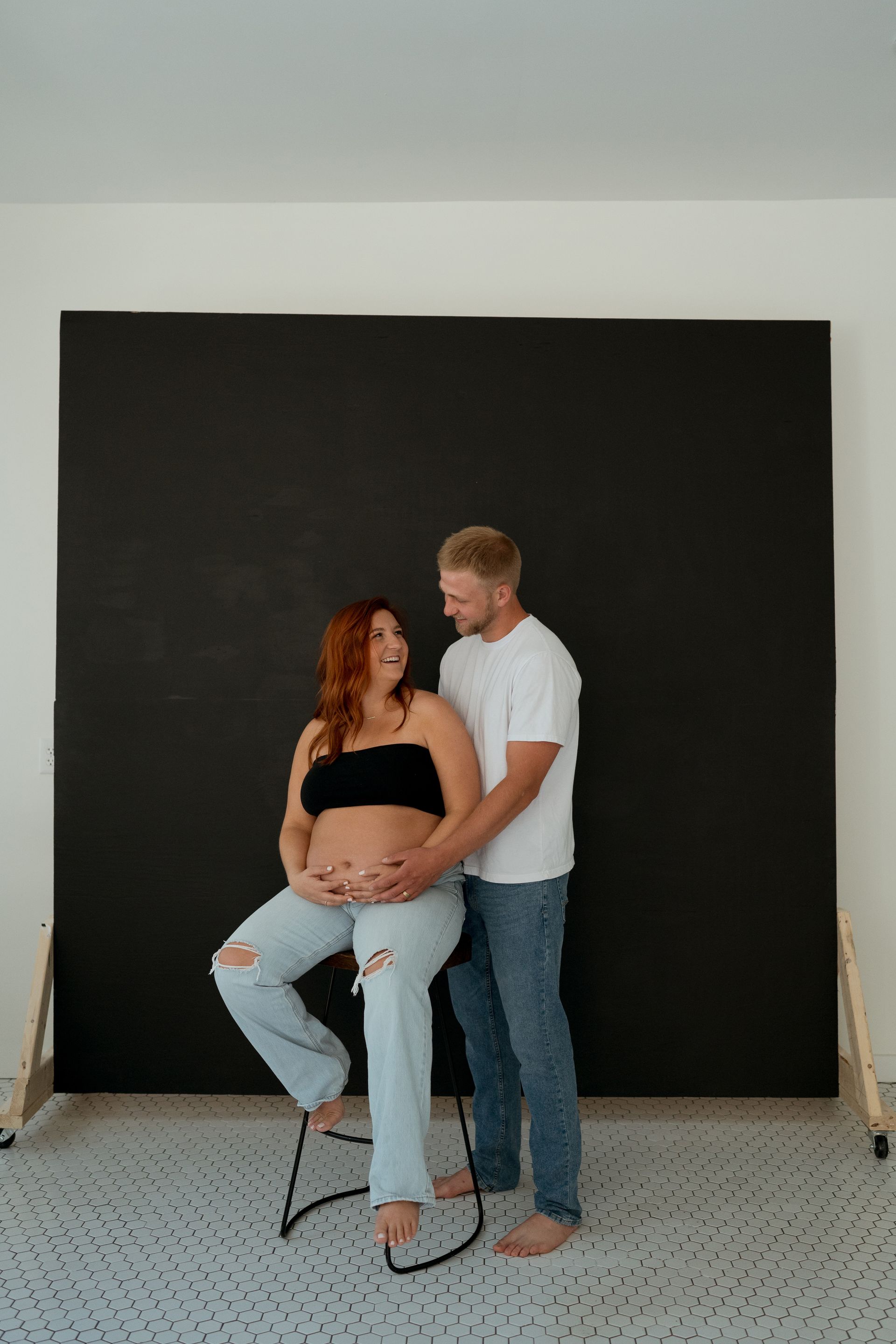 A pregnant woman is sitting on a chair next to a man.