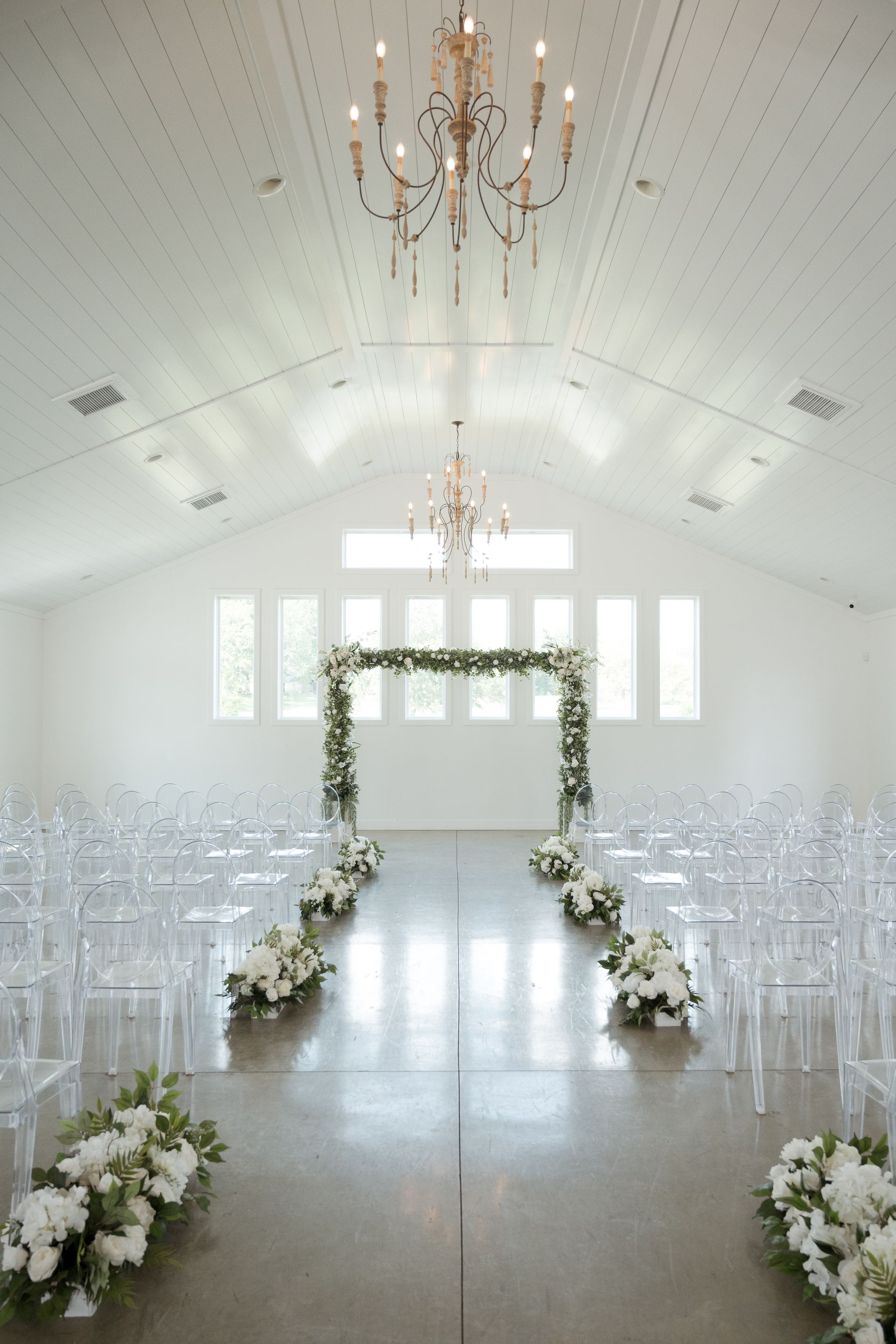 A wedding ceremony is taking place in a church with a chandelier hanging from the ceiling.