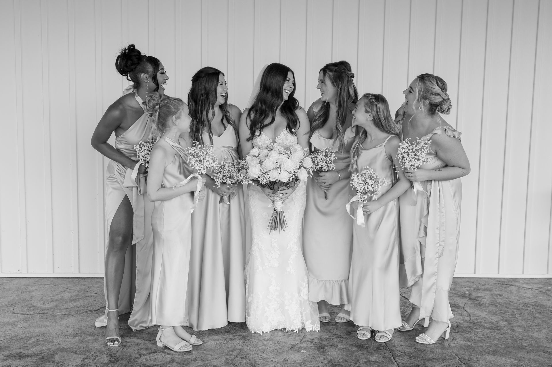A bride and her bridesmaids are posing for a black and white photo.