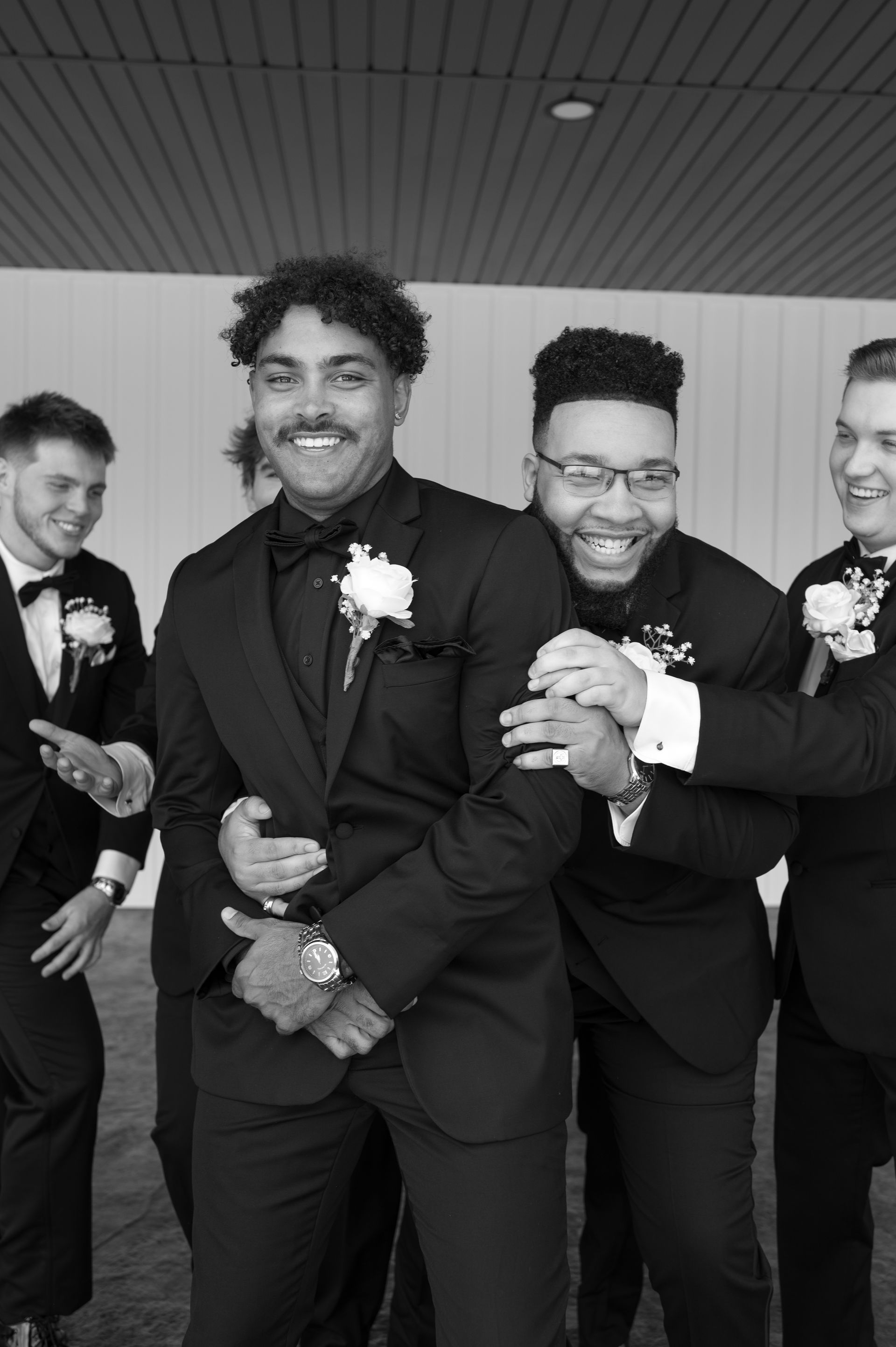 The groom and his groomsmen are posing for a black and white photo.