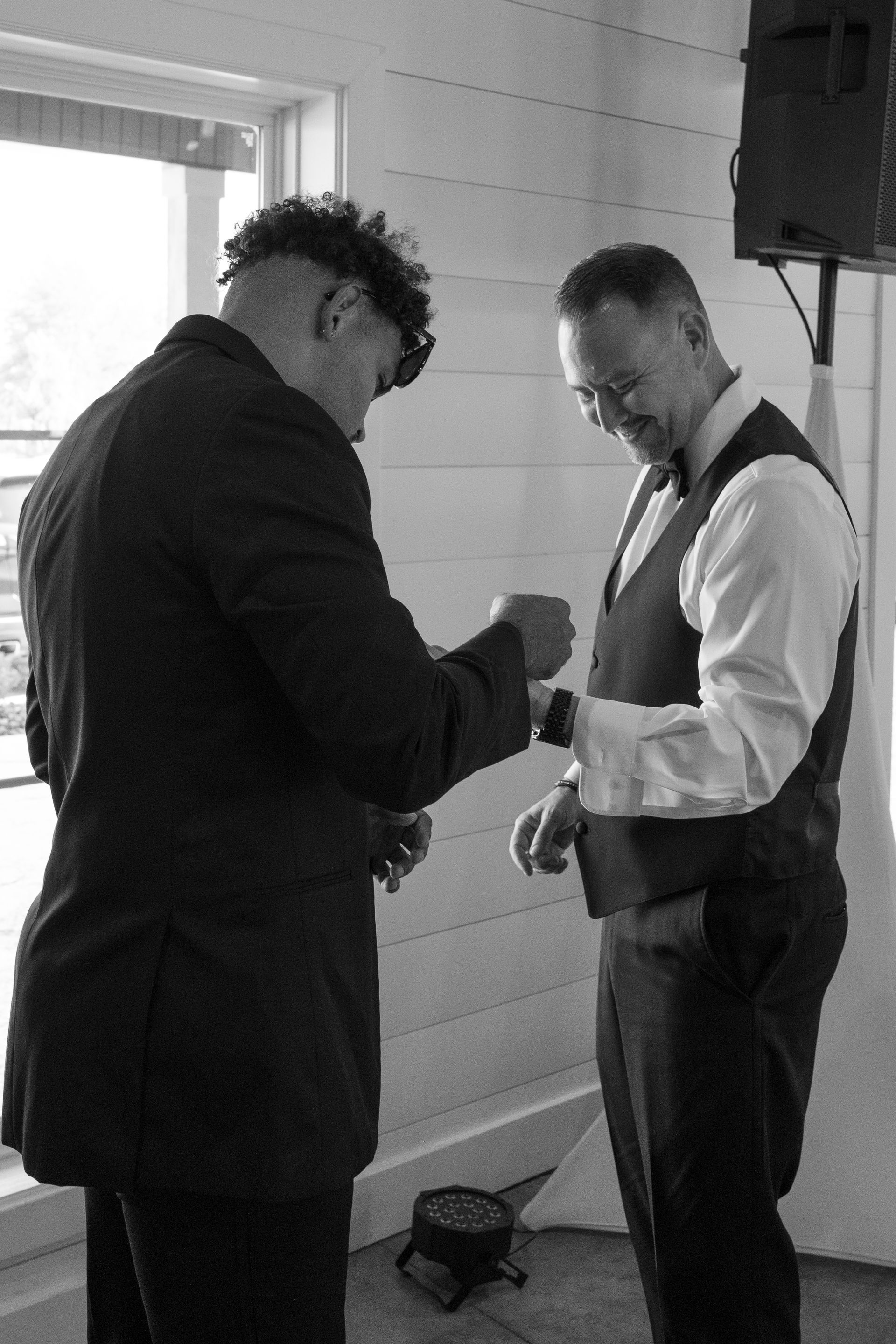 Two men in suits are getting ready for a wedding.