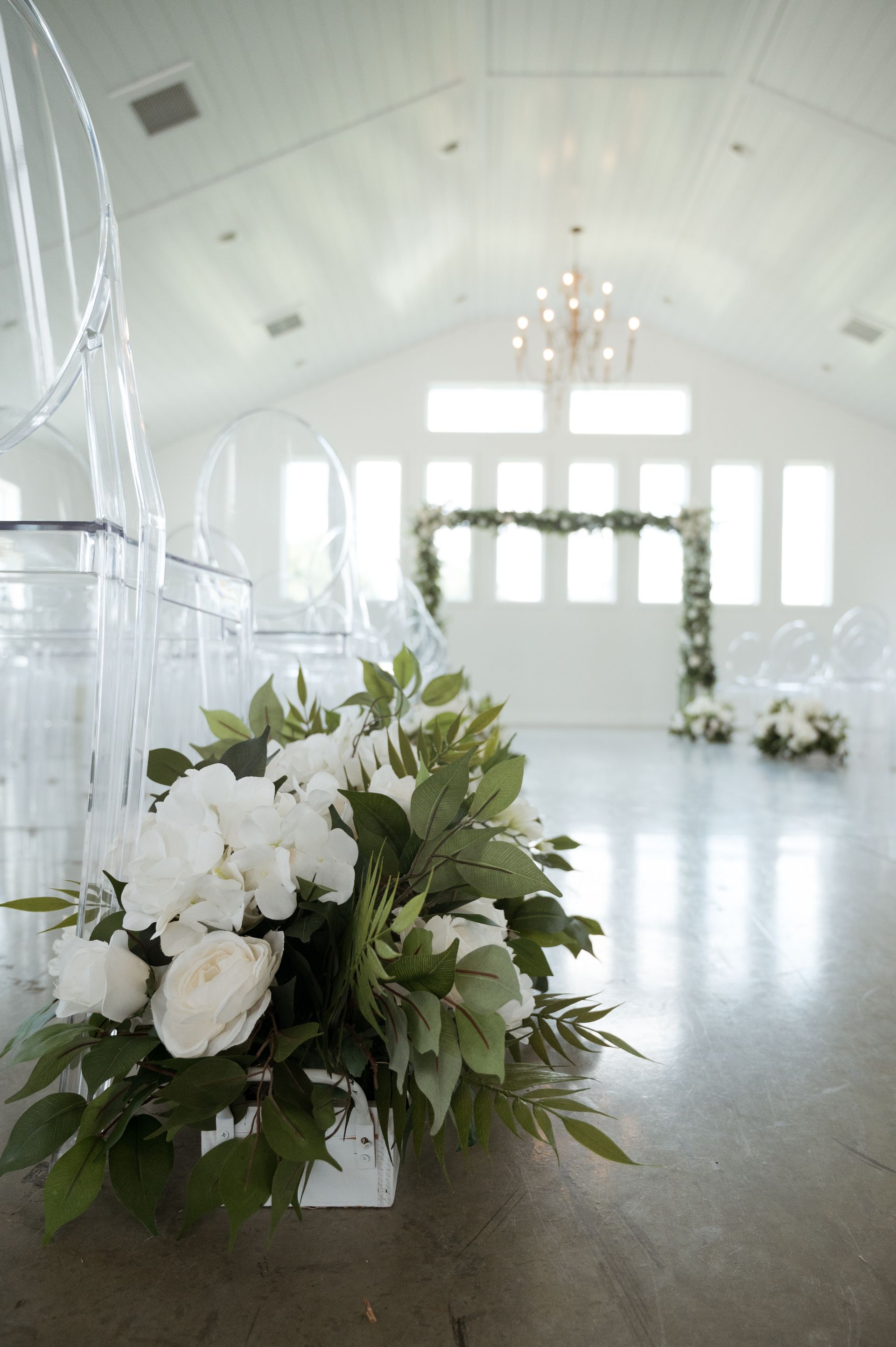 A bouquet of white flowers is sitting on the floor in front of a row of clear chairs.