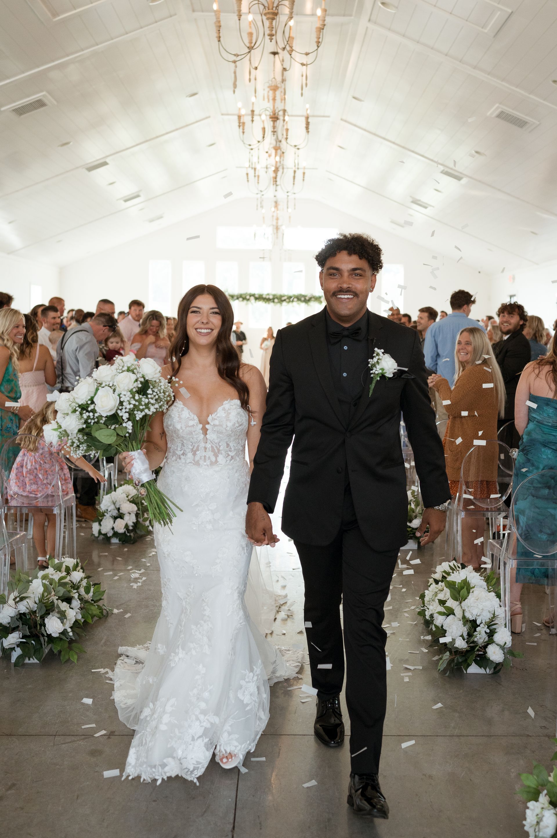 A bride and groom are walking down the aisle holding hands.