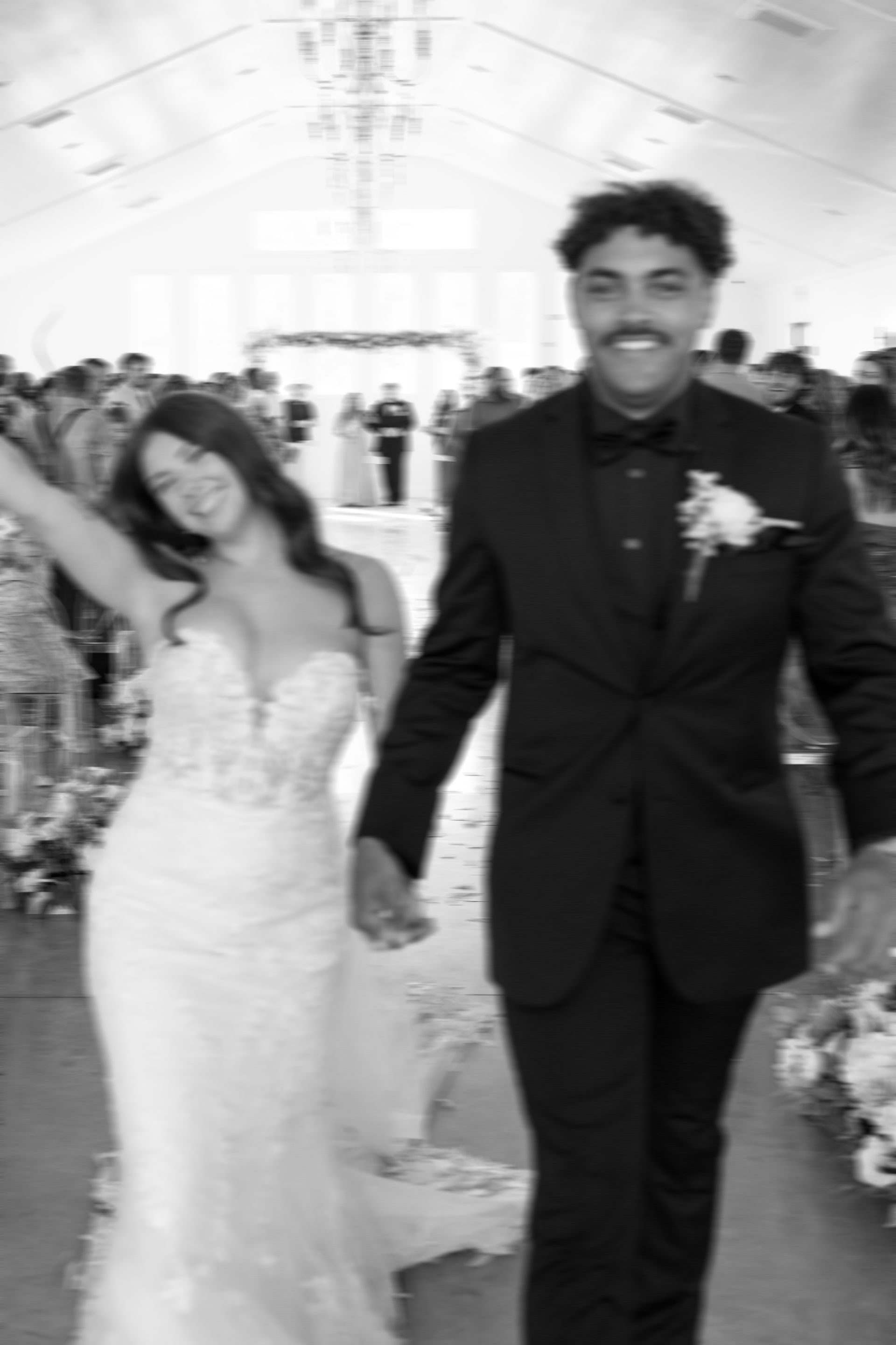 A bride and groom are walking down the aisle holding hands.