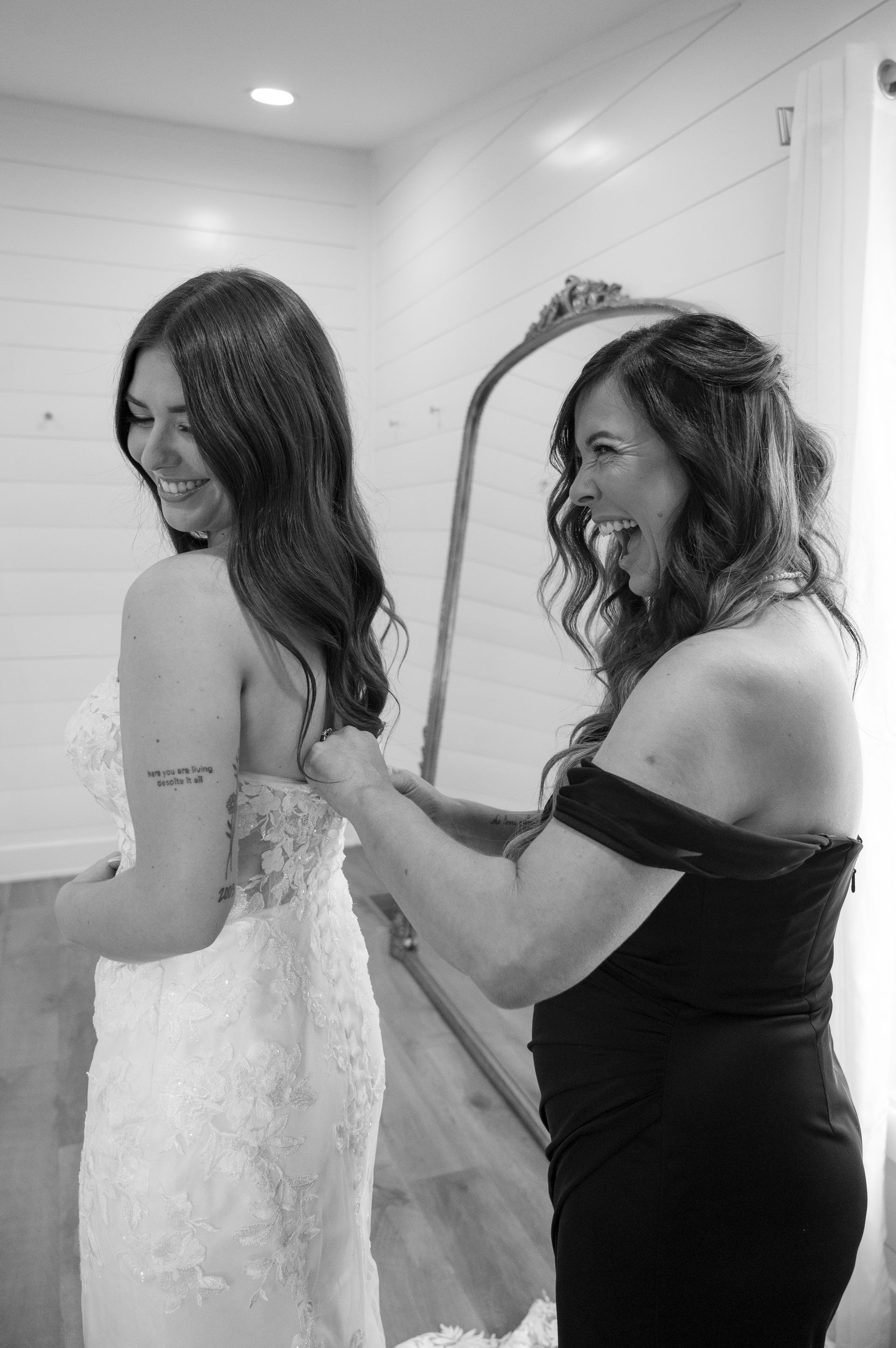 A woman is helping a bride get ready for her wedding.