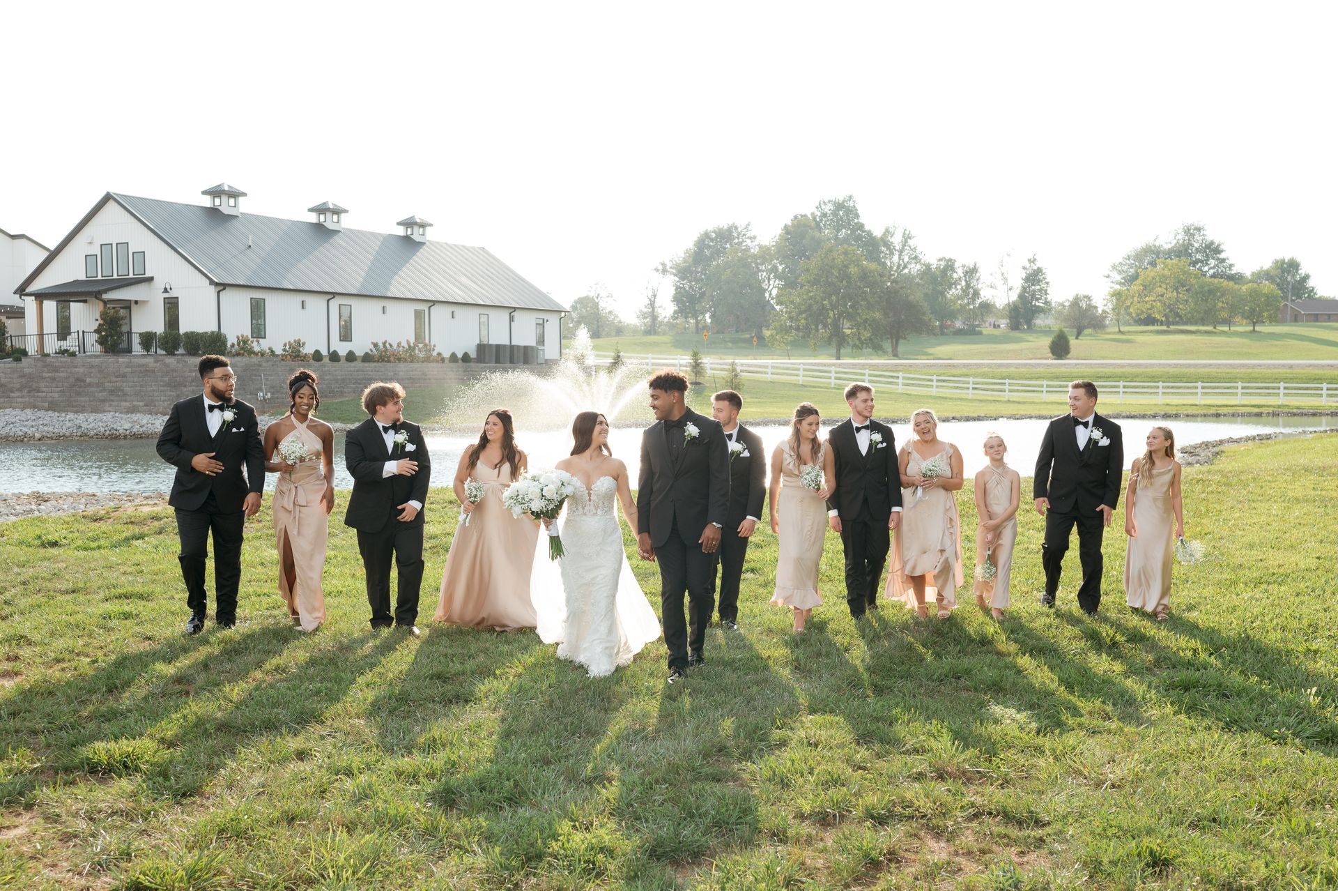 A bride and groom are walking with their wedding party in a field.